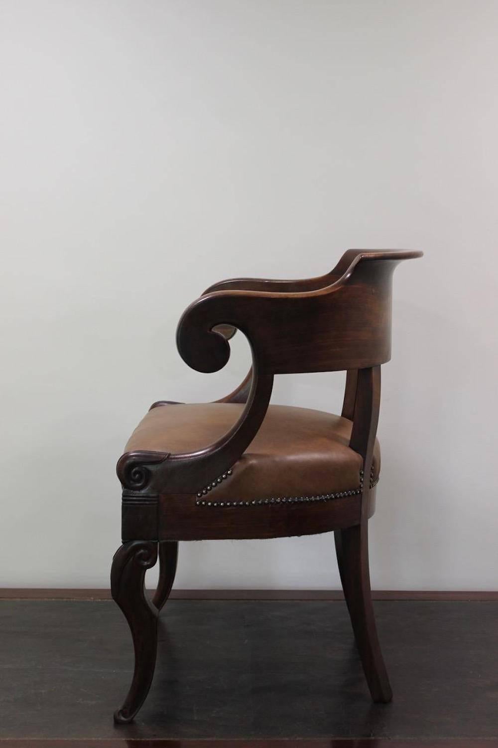 A good quality Louis Philippe mahogany desk chair or 'fauteuil de bureau' with close nailed brown leather upholstery, the frame with accentuated curves and good color and patination, French, second quarter of the 19th century.
