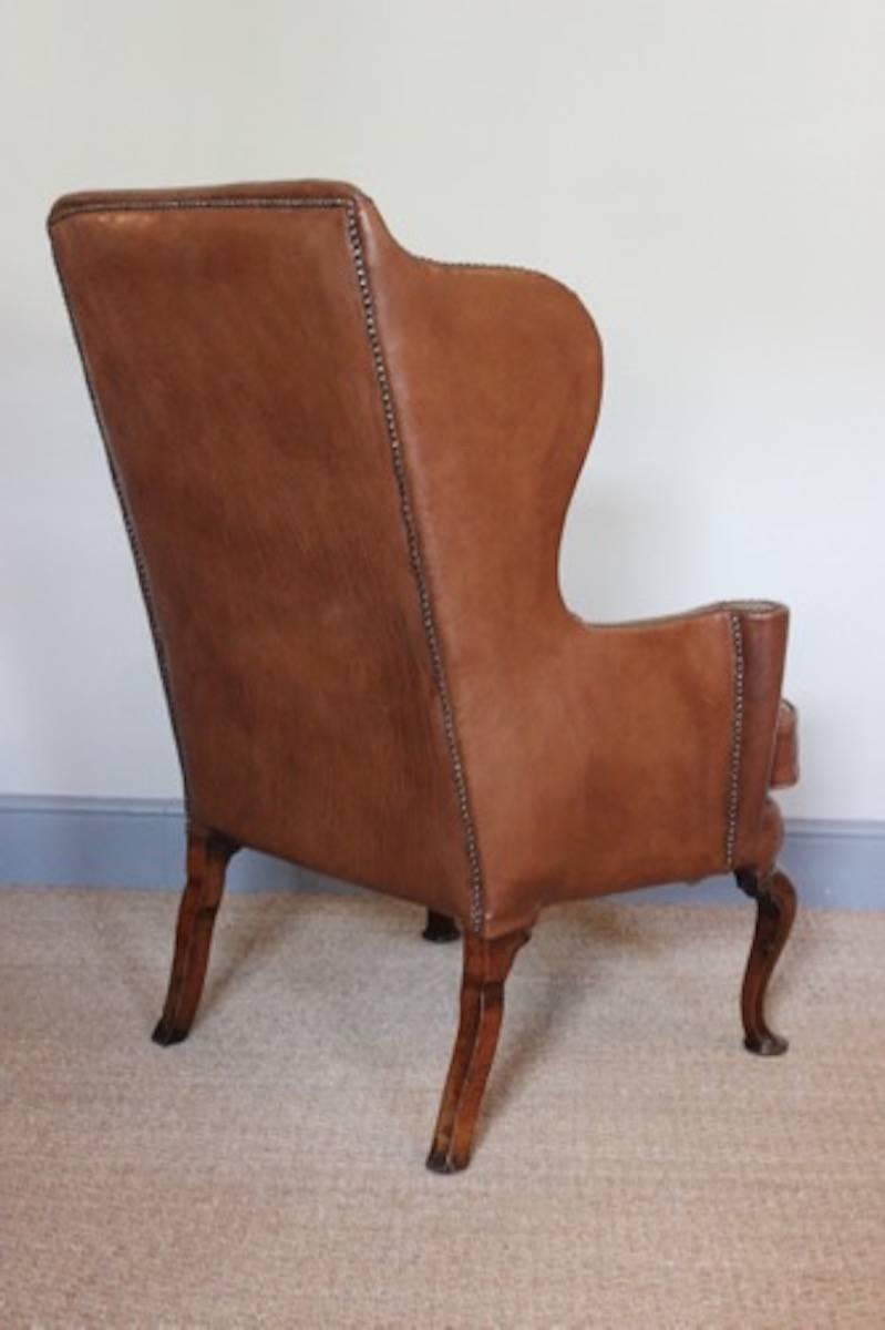 A wonderfully proportioned Queen Anne walnut wing armchair, reupholstered in close-nailed tan leather, English, circa 1710.
 