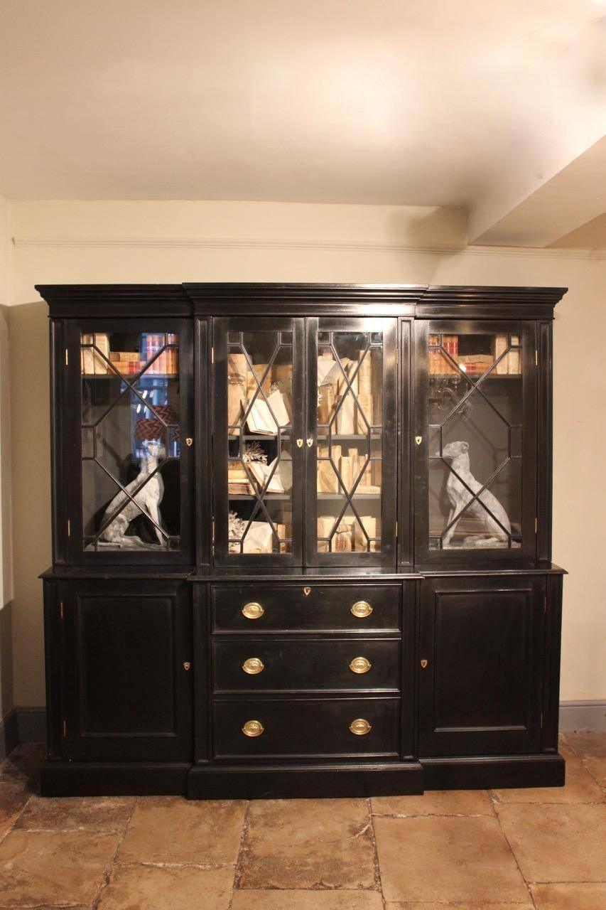 A well-proportioned 19th century ebonized breakfront bookcase with a glazed upper section enclosing adjustable shelves, the base fitted with a secretaire drawer (later ebonized).
 