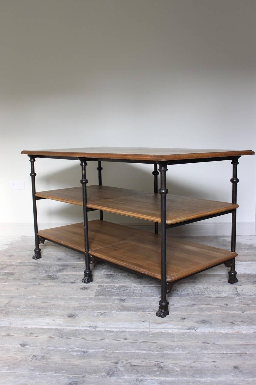 A very practical, circa 1930s French shop counter or display table in iron with adjustable oak shelves, terminating in claw feet, that would make an unusual side or centre table.
 