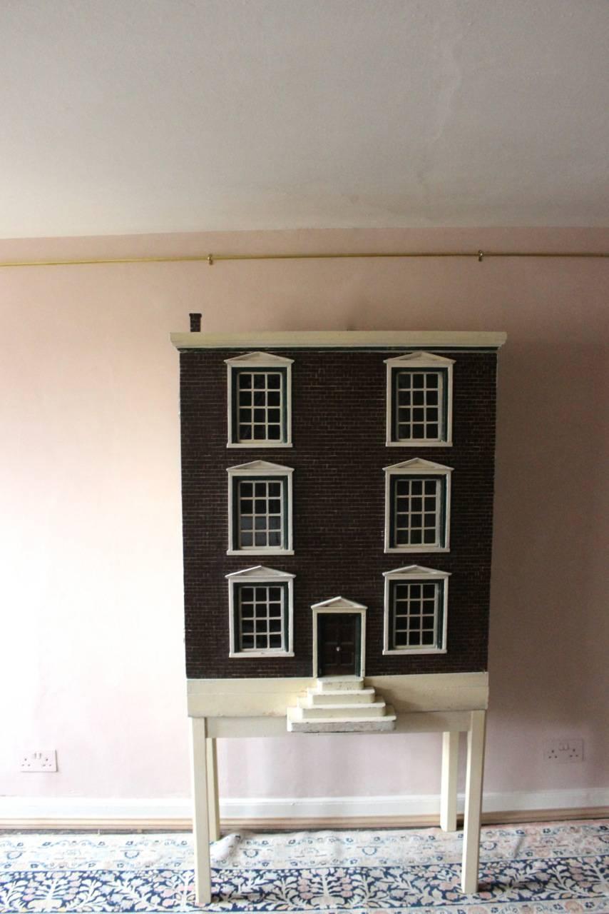 A very charming, mid-20th century, Georgian-style English dolls house of great size, ideal as a drinks cabinet (on a later stand), divided internally into six rooms.