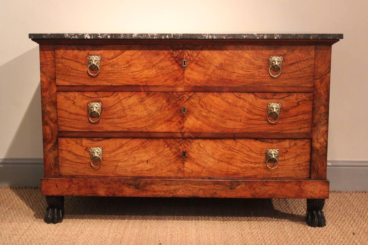 A good quality and well-proportioned Empire commode of highly-figured walnut with a marble top and lion-mask handles, French, early 19th century.