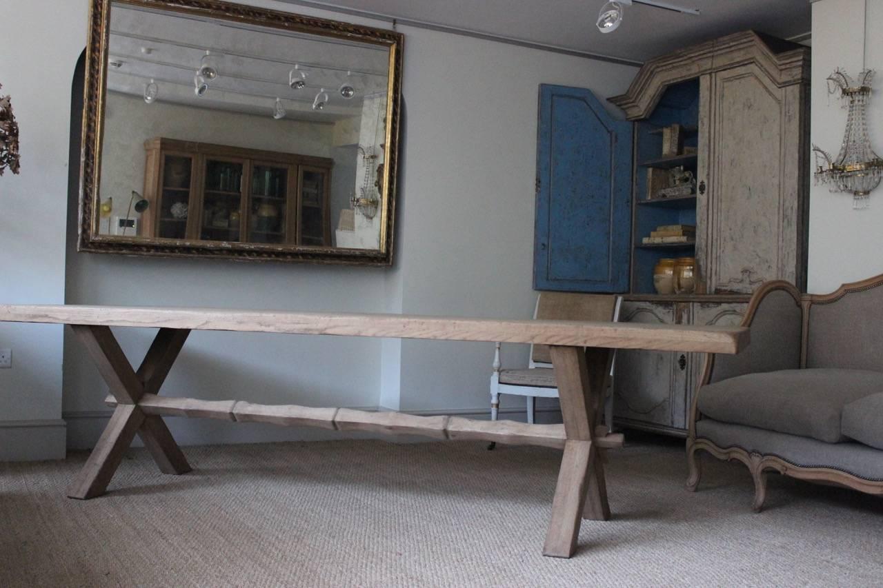 A large mid-20th century bleached oak dining table with X-frame supports and a shaped stretcher that would make a statement in most settings. 

 