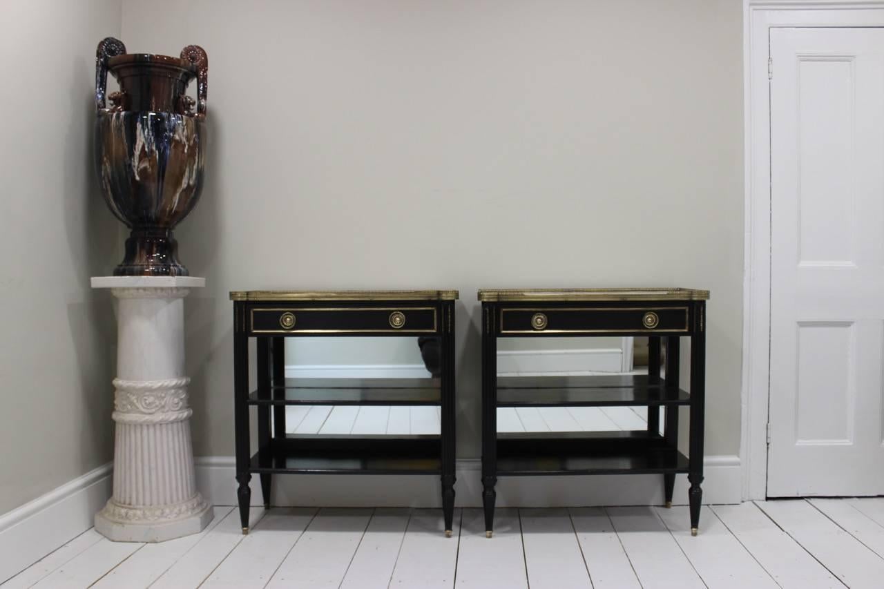 A very stylish pair of Louis XVI style ebonised and gilt-metal mounted console tables, each with a brass gallery, marble top and mirrored back, French, circa 1940s, that would make a statement in most settings.
