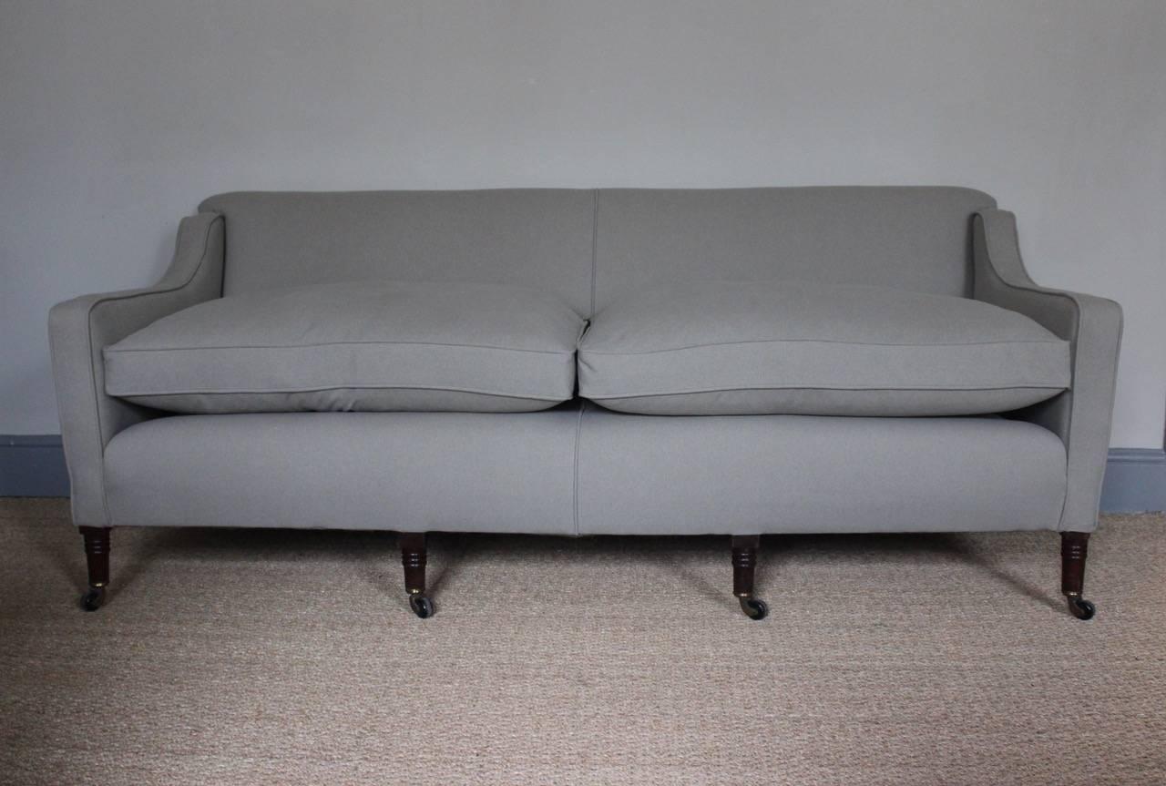 A broad 19th century English country house sofa on ring-turned legs with original castors, and newly upholstered. 

Measures: Seat height 48cm.
 