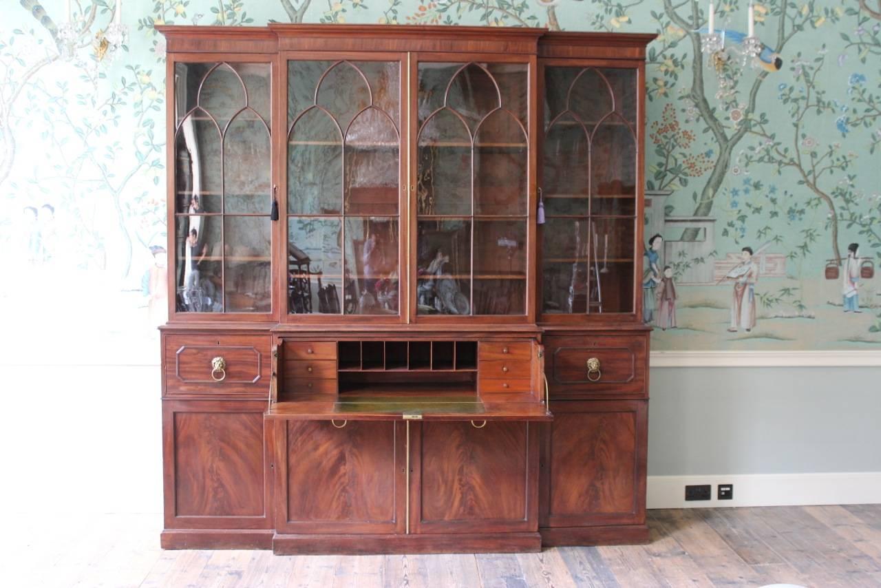 A fine quality, English mahogany breakfront bookcase. The den tilled cornice above two pairs of glazed paneled doors with lancet shaped shaped and adjustable shelves. The projecting lower part with a central pair of doors.

England.