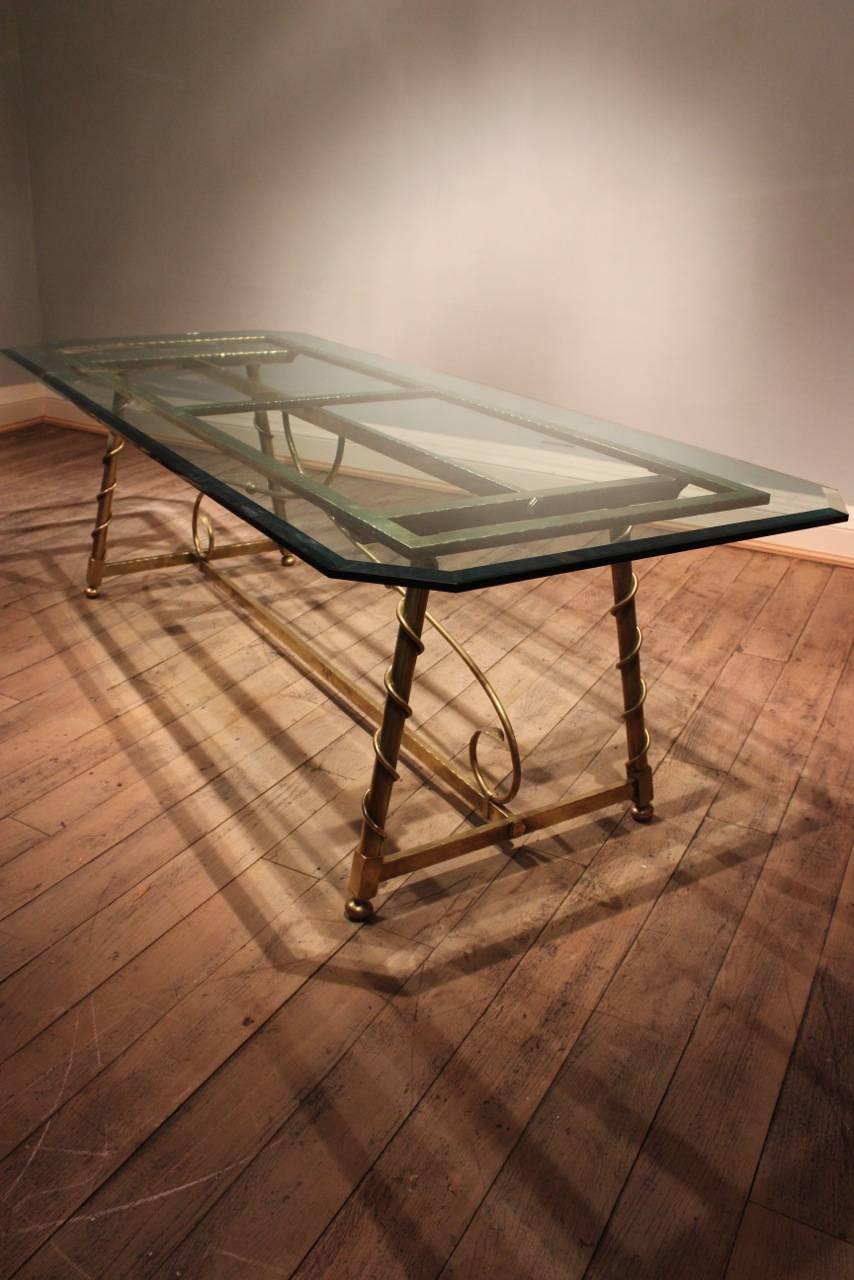 A superb quality and of great proportions, circa 1940s, French dining table in brass, following an 18th century model with a twist. The top in bevelled glass.

This dining table will make a statement in most settings, also would work well as a