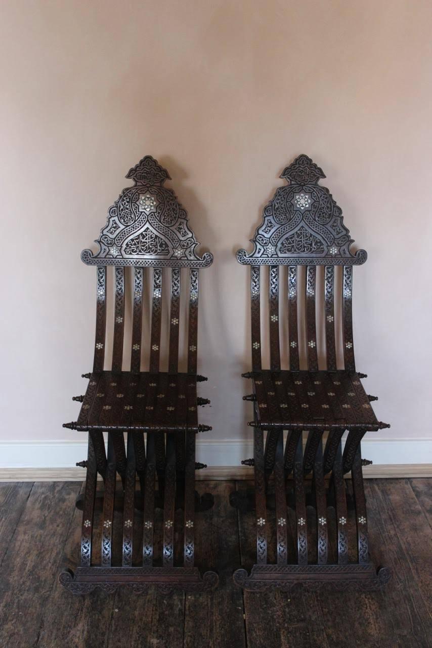 A good quality pair of 19th century Middle Eastern fold-up chairs. The back splats having star-shaped ivory designs and Arabic scripts throughout.