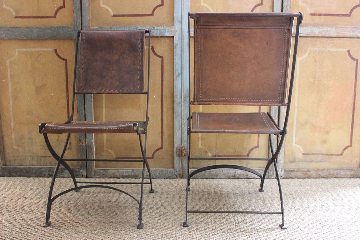 An unusual and very good quality set of six black-painted iron and tan leather folding chairs.