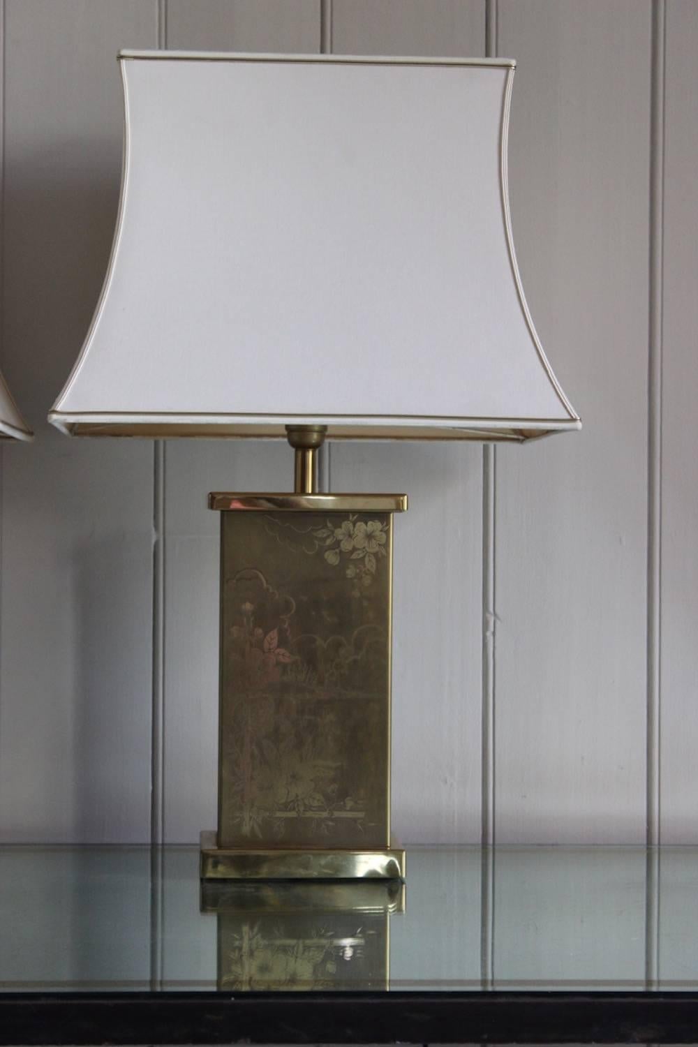 A smart and stylish pair of polished brass table lamps of rectangular form with engraved chinoiserie decoration and bespoke concave-sided shades, France, 1970s.