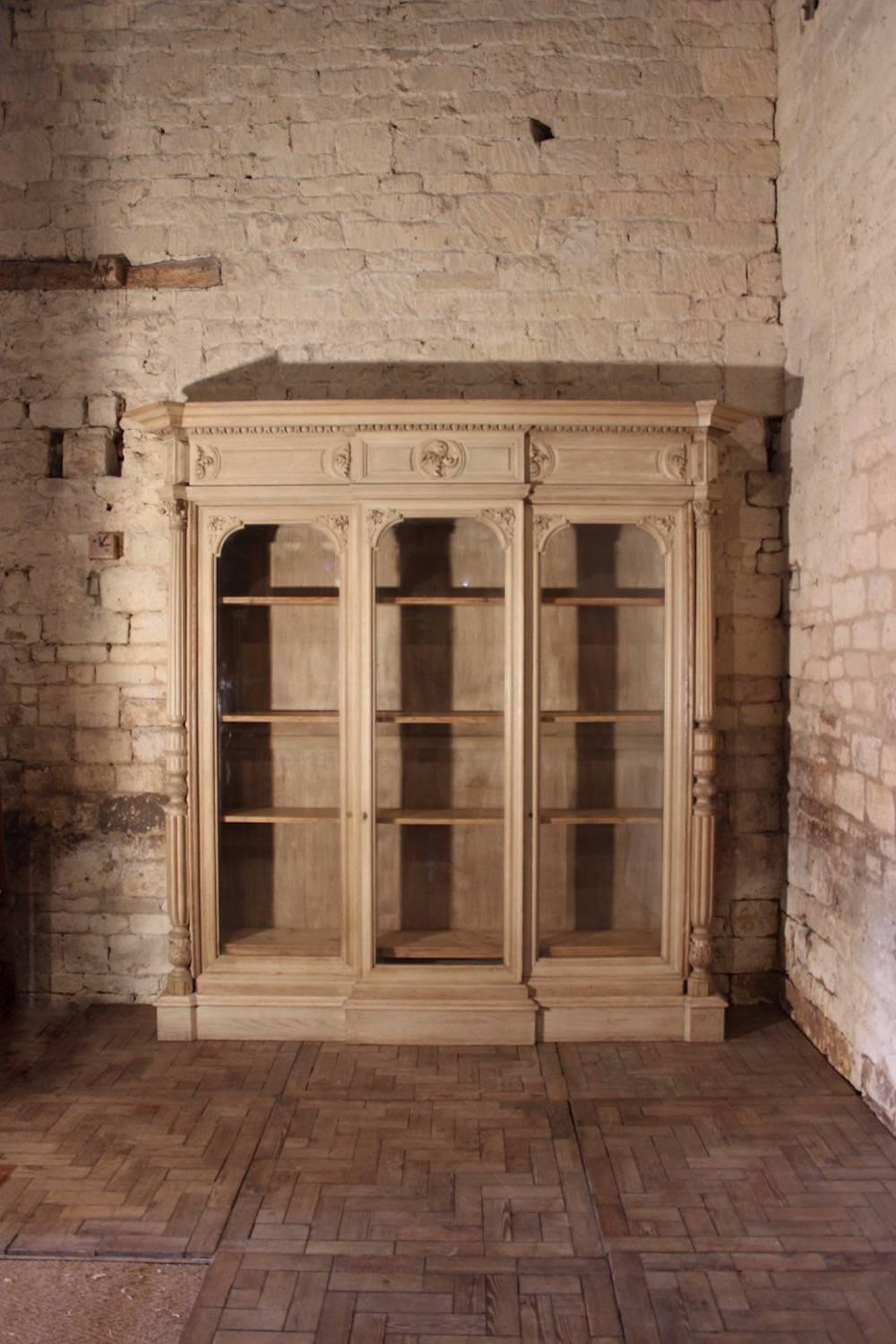 A large carved and bleached oak bookcase in the Renaissance style, with three doors enclosing shelves, English, circa 1860.