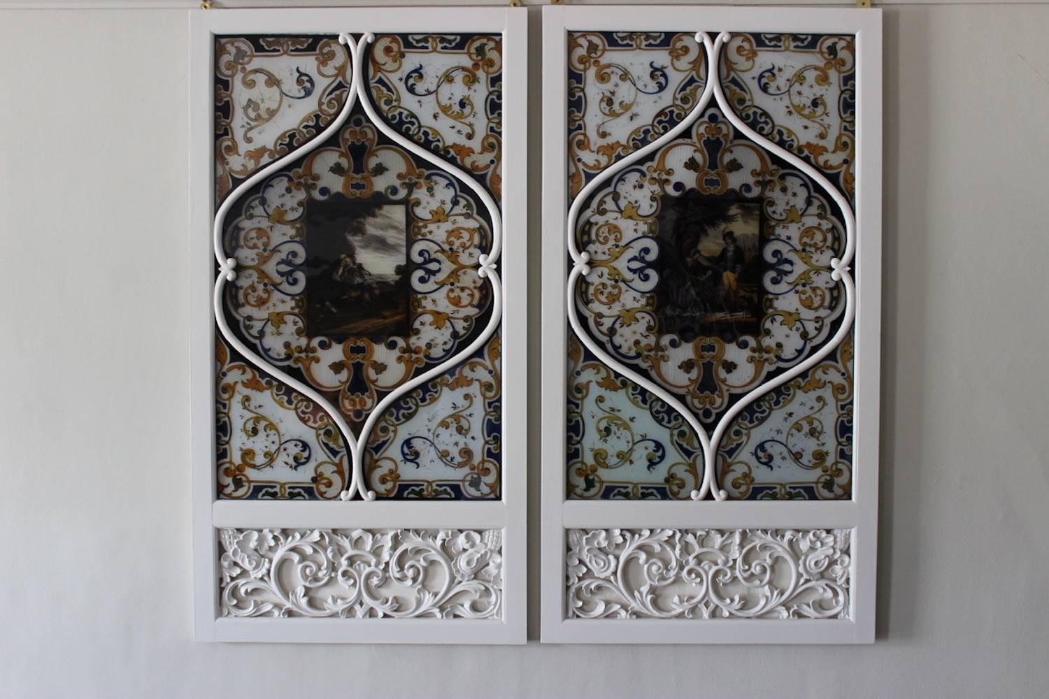 A charming and highly decorative pair of painted glass panels in a historical style, the central cartouche of each depicting a pastoral scene with figures, in pierced and carved white-painted frames (probably originally part of an architectural