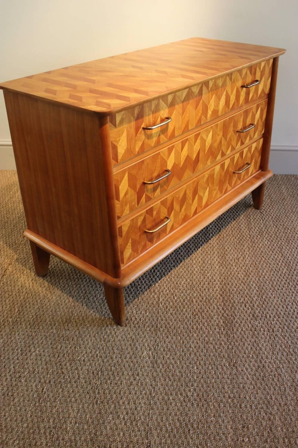 A stylish and decorative mid-20th century geometric parquetry three-drawer commode in cherrywood, French, 1950s.