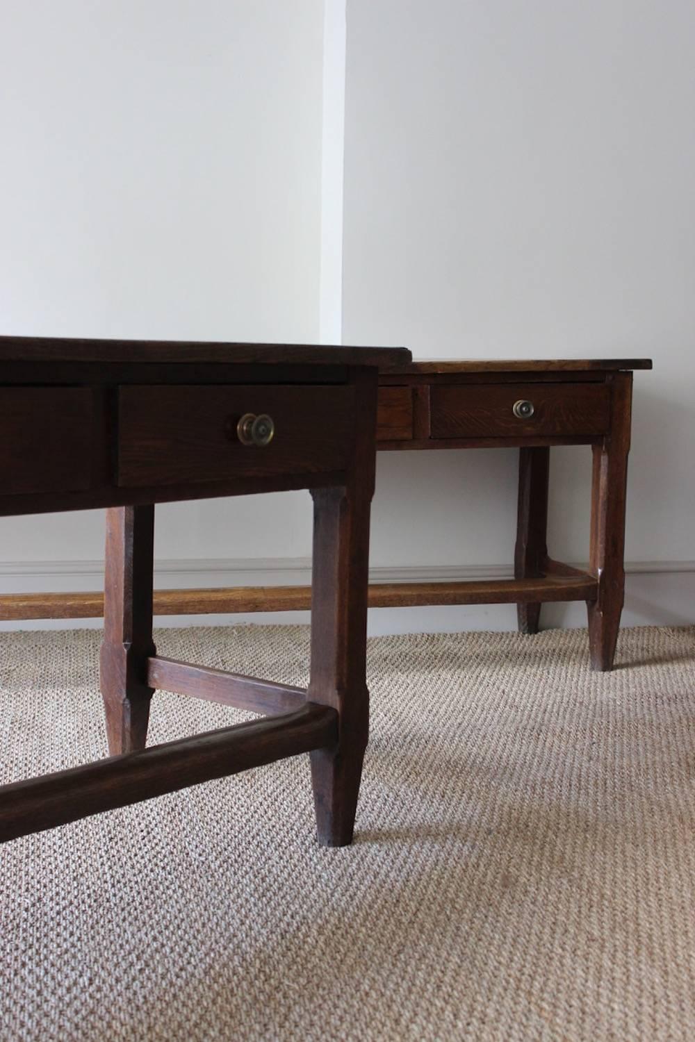 A large and impressive pair of early to mid-19th century French oak serving tables, each with six drawers, on chamfered square legs and tapering feet.