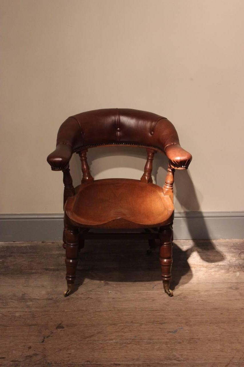 A good pair of walnut and close-nailed leather 'Captain's' chairs or desk chairs, each with a curved upholstered back and saddle seat, on castors, English, circa 1880.
 