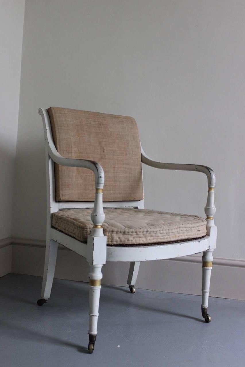 A smart and decorative Regency white-painted and parcel-gilt library or desk chair, with its original horsehair padded back and cushion, on castors, English, early 19th century.
 