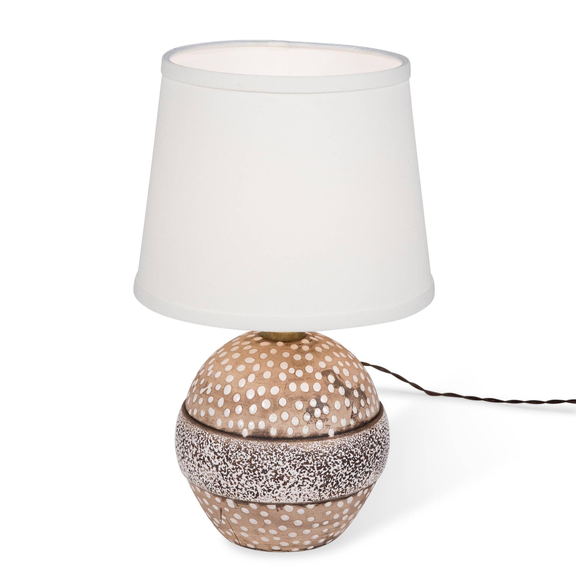 Glazed and spotted ceramic table lamp, of spherical form, with central darkened band by Louis Dage, France, 1930s. Overall height 14 1/2 in, diameter of base 5 1/2 in. Shade measures top diameter 7 in, bottom dia 9 in, height 7 in.
