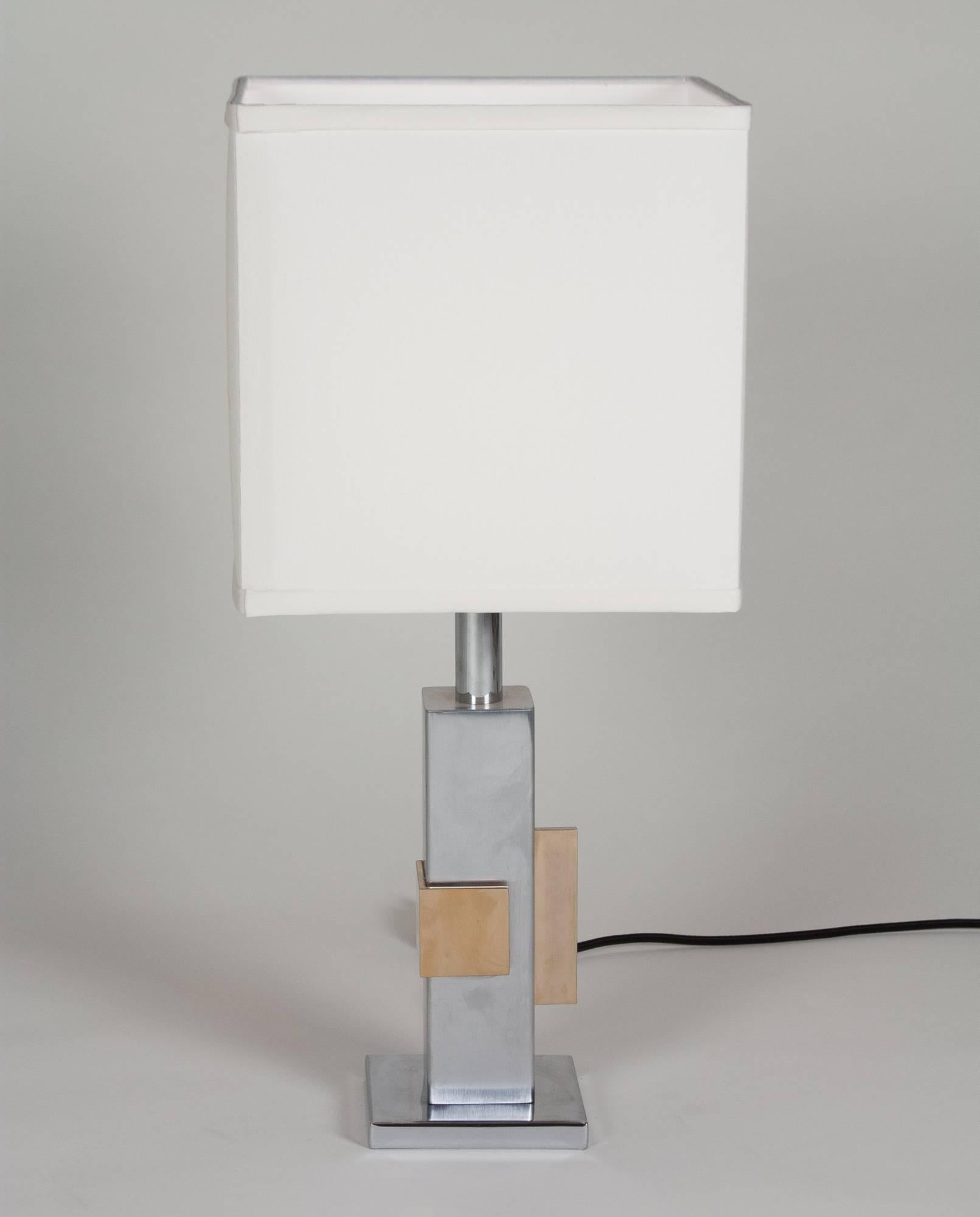 Chrome and bronze table lamp, the square chrome column having two applied bronze geometric elements, French, 1970s. Measures: Overall height 22 1/2 in, base measures 4 3/4 in square. Shade measures 10 in cubed. 
 