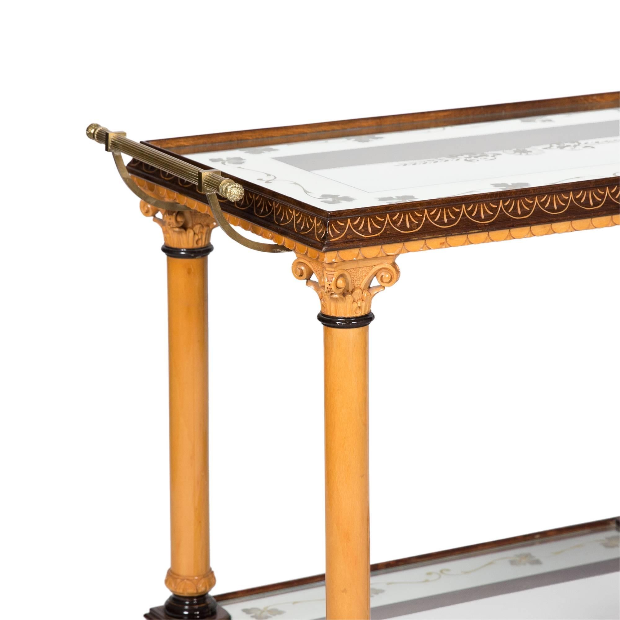 Two-tier maple serving cart, neoclassical style column legs, the surfaces glass with reverse painted mirror border, brass handles, darkened and carved edgework, United States 1980s. Measures: Height 30 1/2 in, width 34 1/2 in, depth 17 1/2 in.