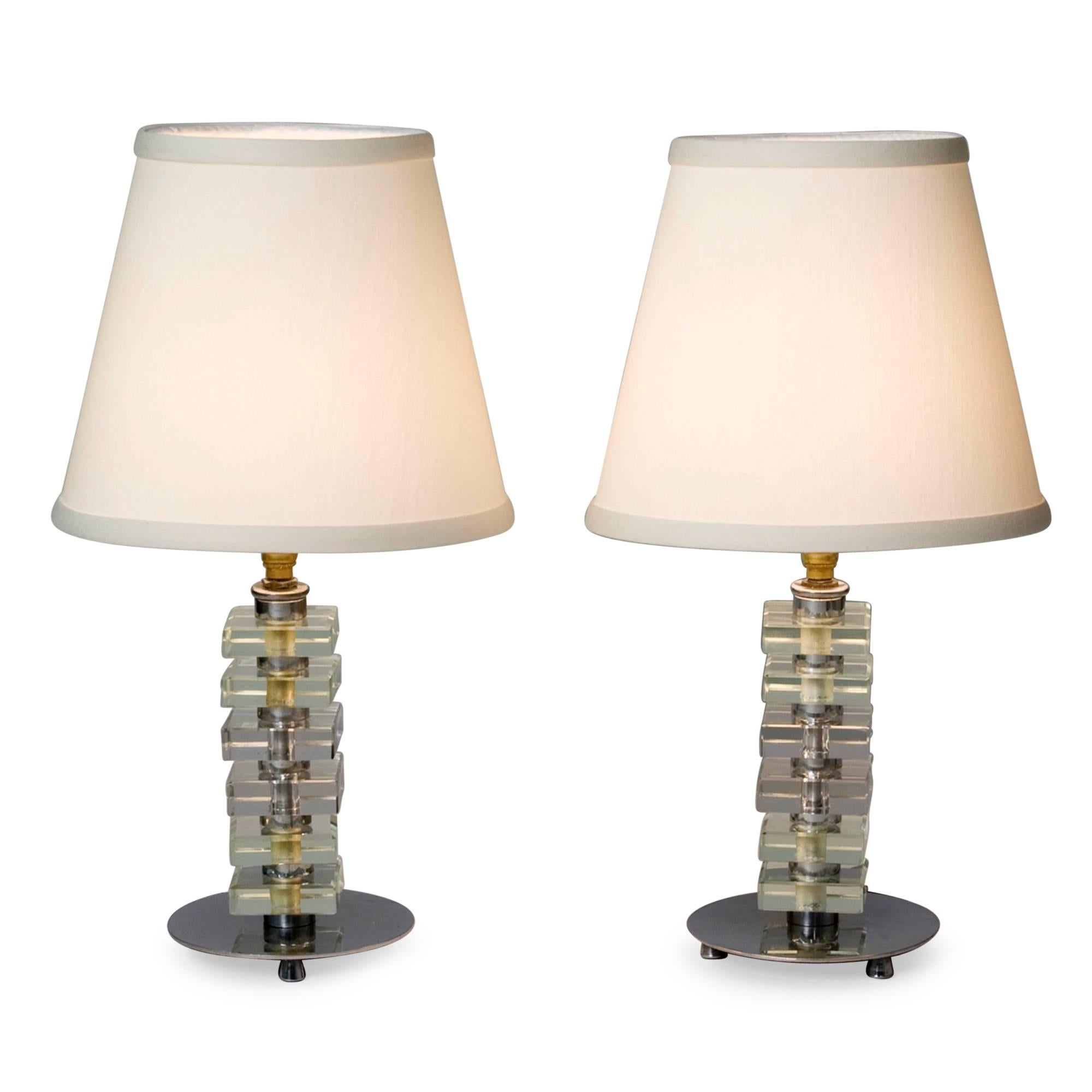 Pair of stacked glass boudoir lamps, the square glass elements separated by nickeled bronze discs, and resting on a larger nickeled bronze base having four feet, in custom silk shades, in the style of Jacques Adnet, French 1930s. Overall height 15