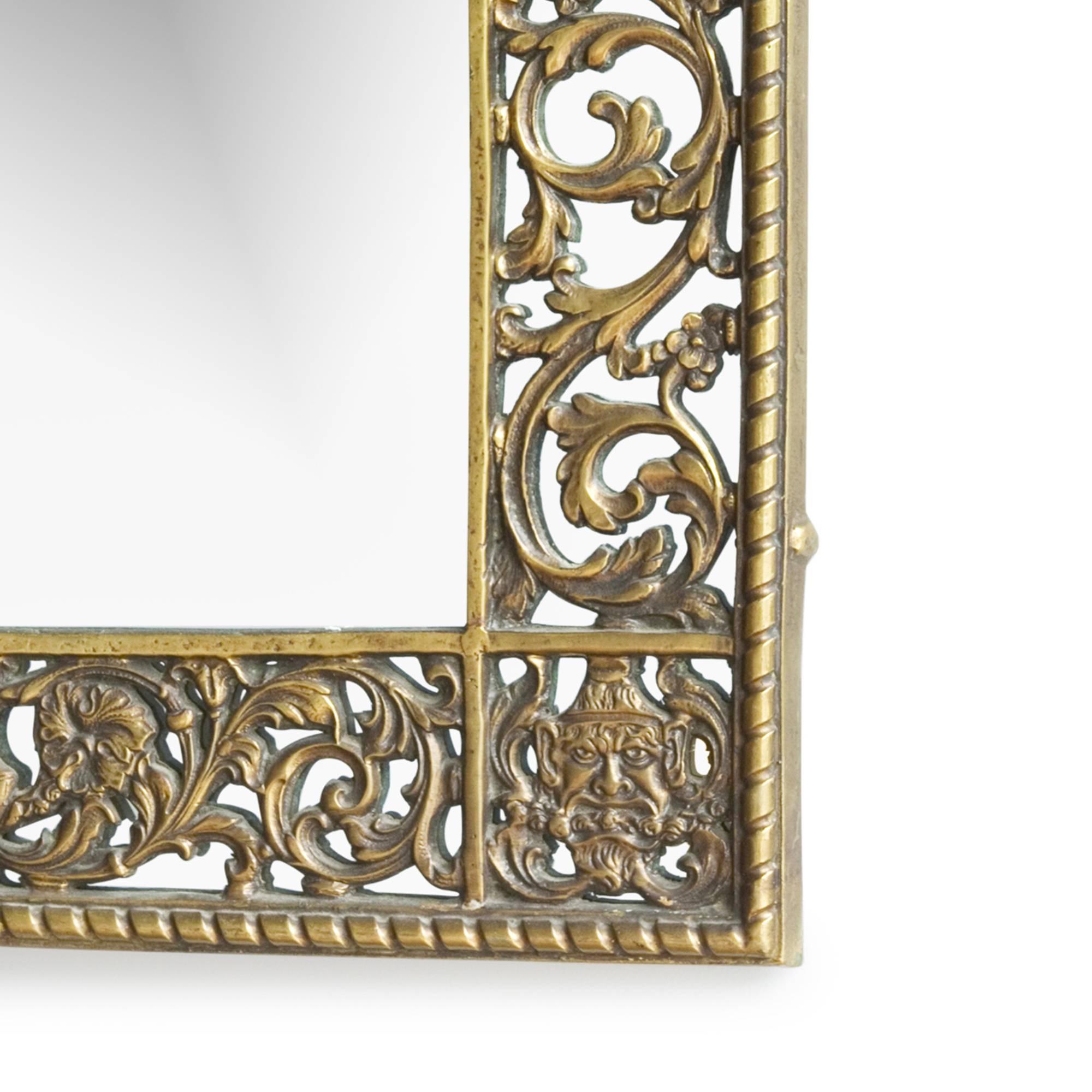 Cast bronze arched top foliate and figural form frame mirror, detailng  masks, urns and scrolling leafage, by Oscar Bach, American 1920s. Height 34 1/4 in, width 18 3/4 in. (Item #1692)
