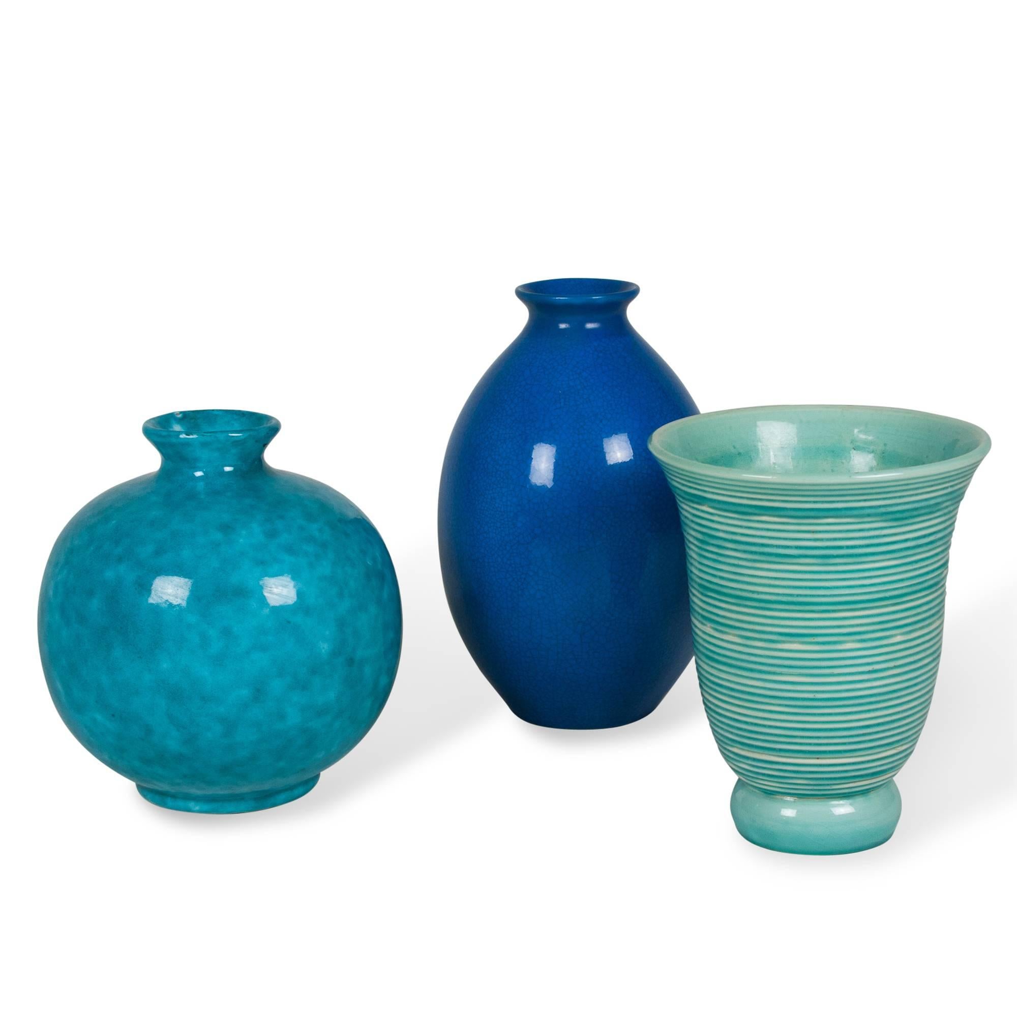Set of three ceramic vases: 
On left: Mottled blue glazed ceramic vase, spherical shape with pinched neck, by Jerome Massier, Vallauris, France, 1930s. Signed to underside. Height 10 in,largest diamter 8.5 in. (Item #1804). 
In Center: Tall blue