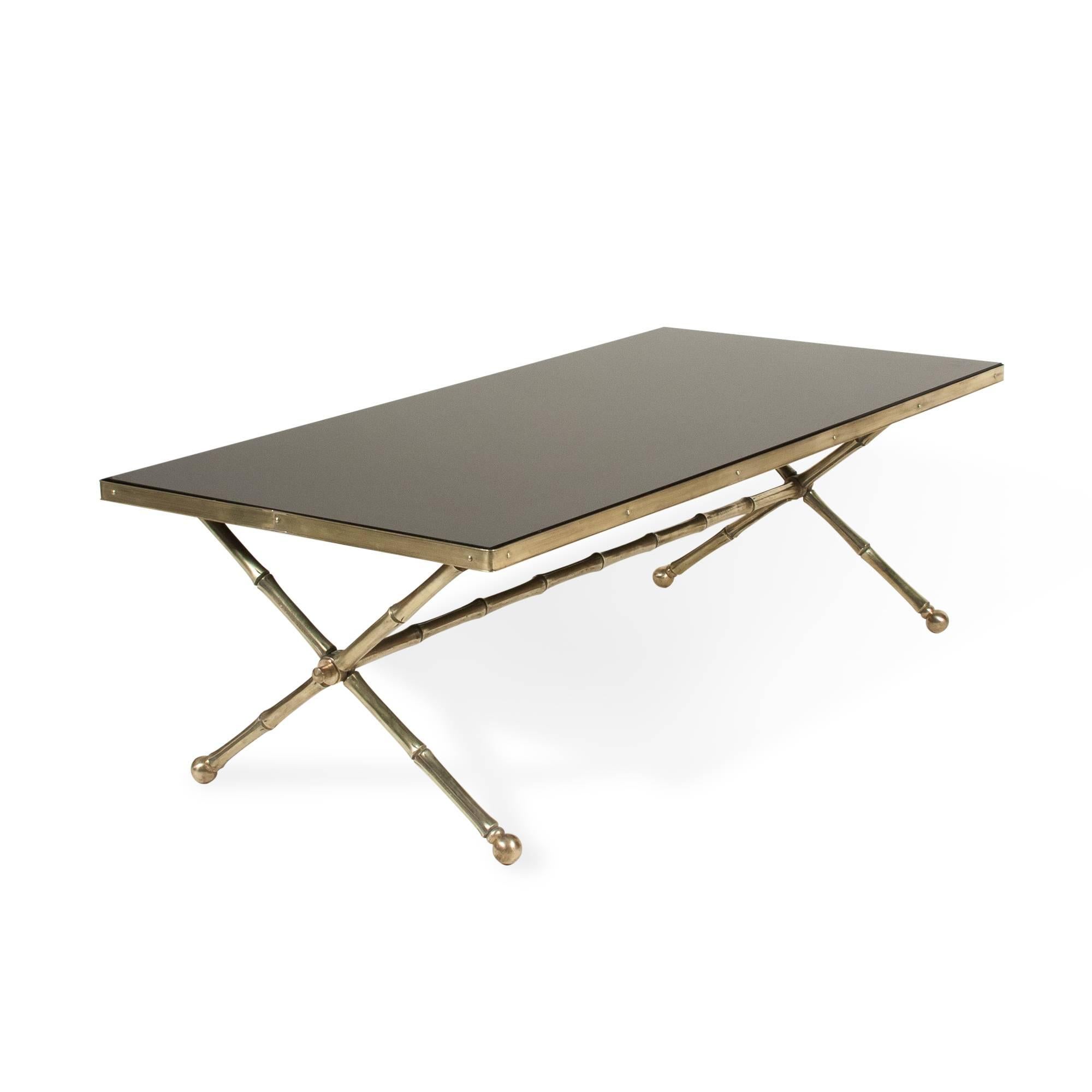 Rectangular black glass top coffee table, bronze faux bamboo frame, crossed legs at either end, with cross stretcher, French, 1960s. Measures: Length 40 in, width 19 1/2 in, height 13 in.
 