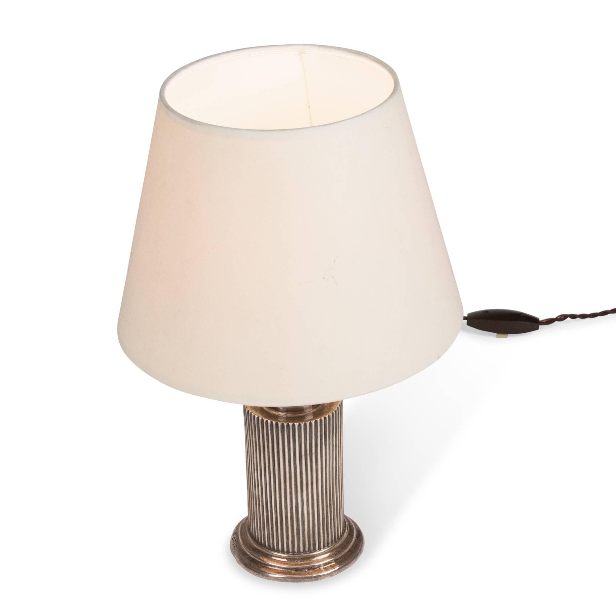 Silver plate small table lamp, a simple fluted cylindrical column with stepped base, France, 1930s. Measures: Overall height 12 1/4 in. Shade measures top diameter 5 in, bottom diameter 7 1/2 in, shade height 6 1/2. Base is 3 1/4 in diameter. (Item