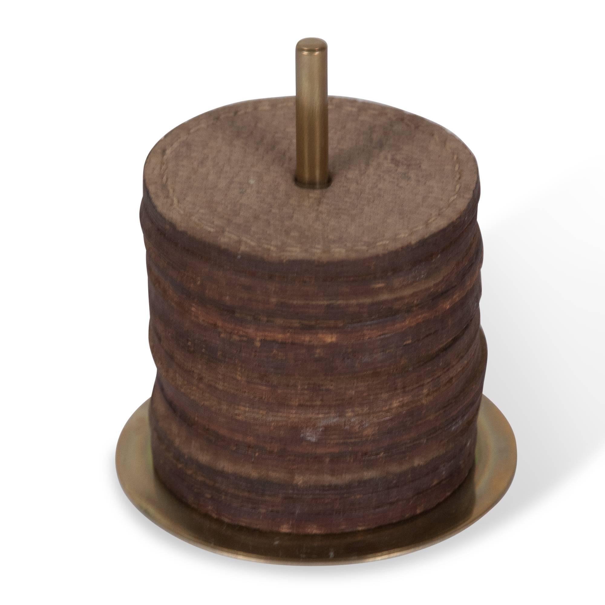 Set of stackable stitched leather coasters, on a brass rod base, by Carl Auböck, Austria, 1950s. Measures: Height 3 1/4 in. Diameter of base 2 3/4 in. Diameter of coasters 2 1/4 in.