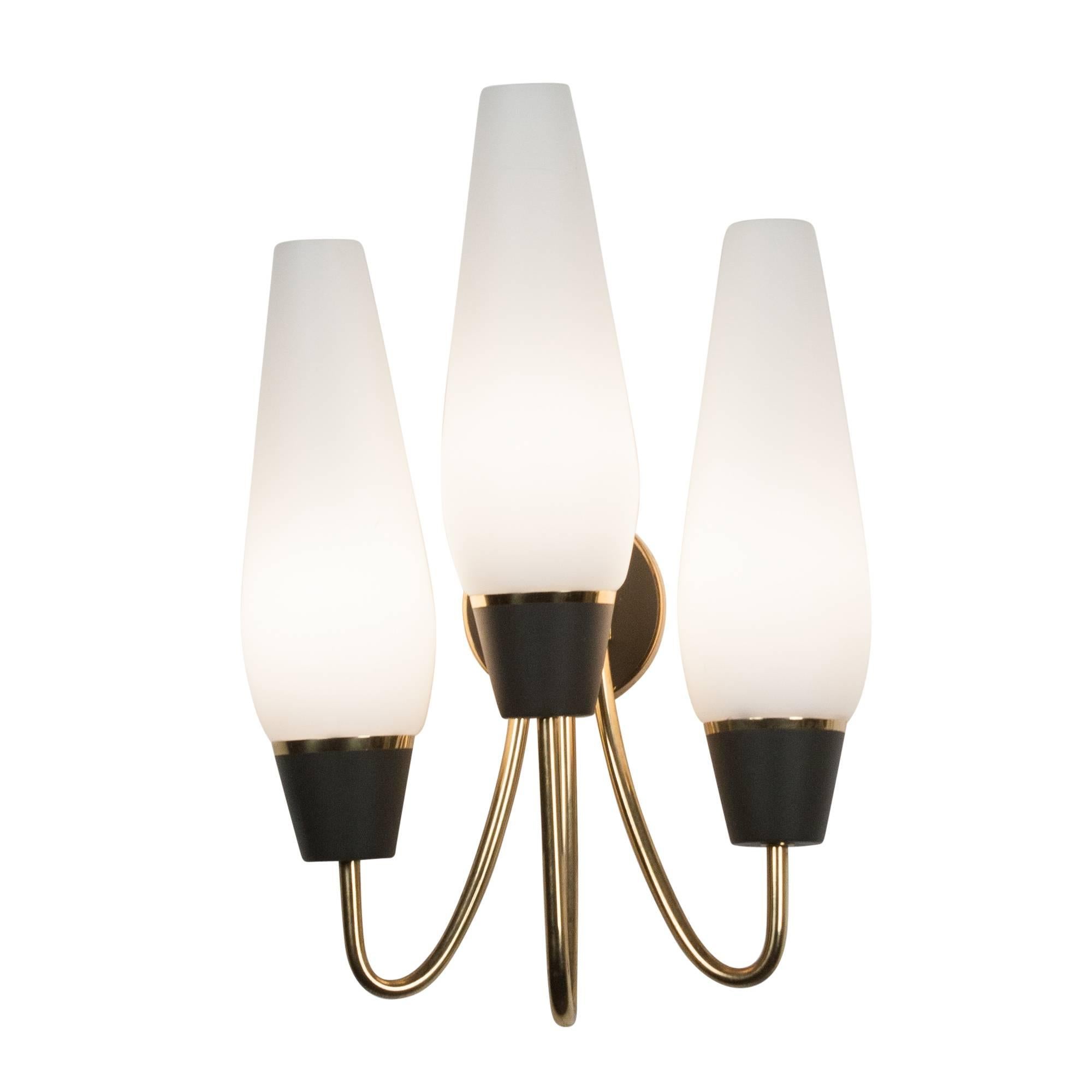 Pair of three-arm wall sconces, curved brass arms leading to black metal housing which supports a frosted glass tapered shade, German 1960s. Measures: Overall height 13 in, width 8 in, depth 5 1/2 in.

A third matching sconce available.