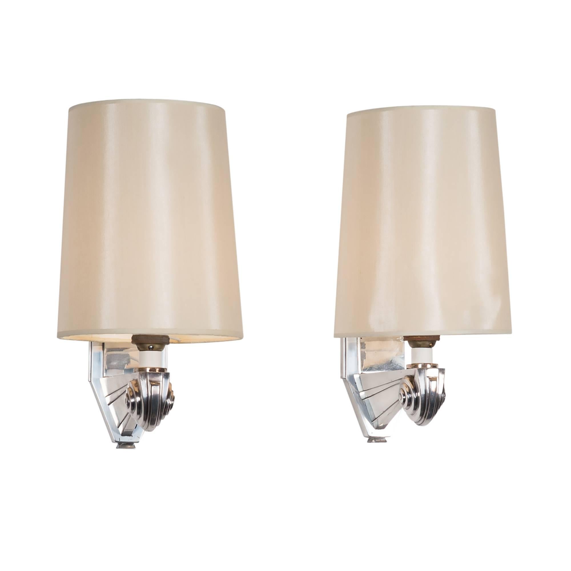 Pair of nickeled bronze one arm sconces, scroll arm, custom linen shades, France 1930s. Overall height 12 in, width 6 in, depth 8 in. Shades measure top diameter 5 in, bottom diameter 6 in, height 8 in.
  