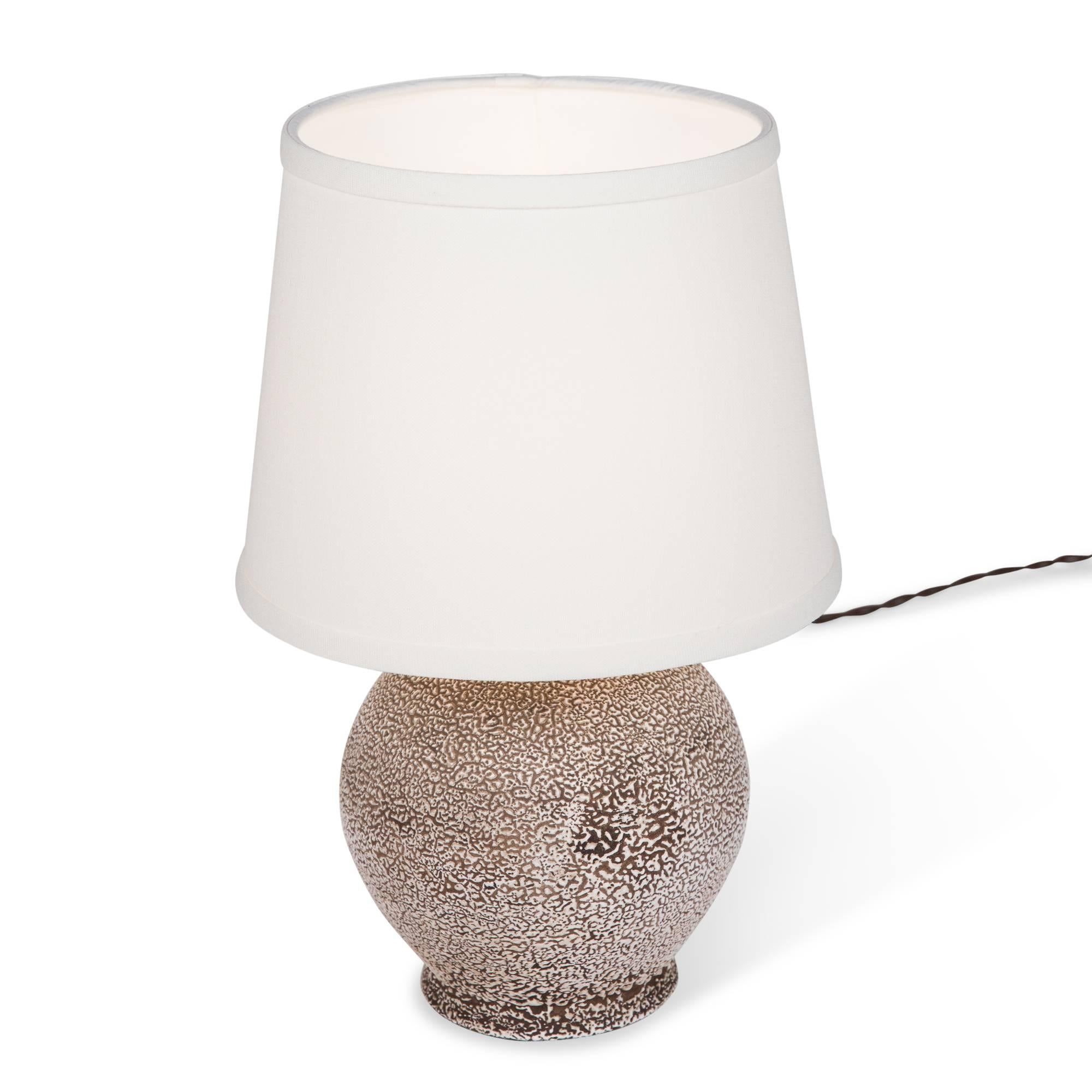 Lightly spotted ceramic table lamp, of spherical form by Louis Dage, France, 1930s. Overall height 14 1/2 in, diameter of base 5 1/2 in. Shade measures top diameter 7 in, bottom dia 9 in, height 7 in.