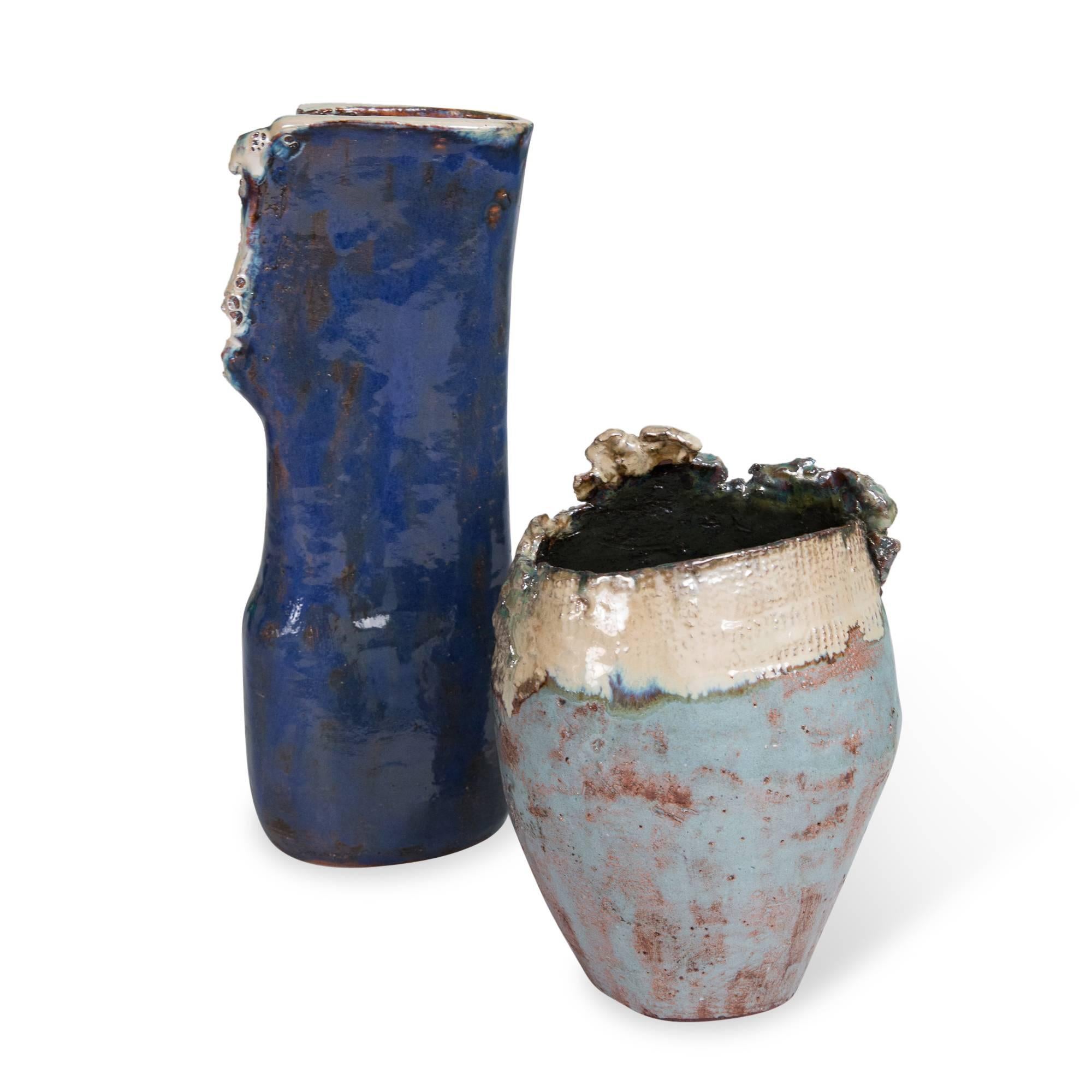 Set of two:
On left:
Blue glazed ceramic vase, with rough opening at top and side, and silver glaze accents, by Juliette Derel, France, late 20th century. Incised signature to underside. Measures: Height 12 in, width 5 in, depth 3 in.

On right: