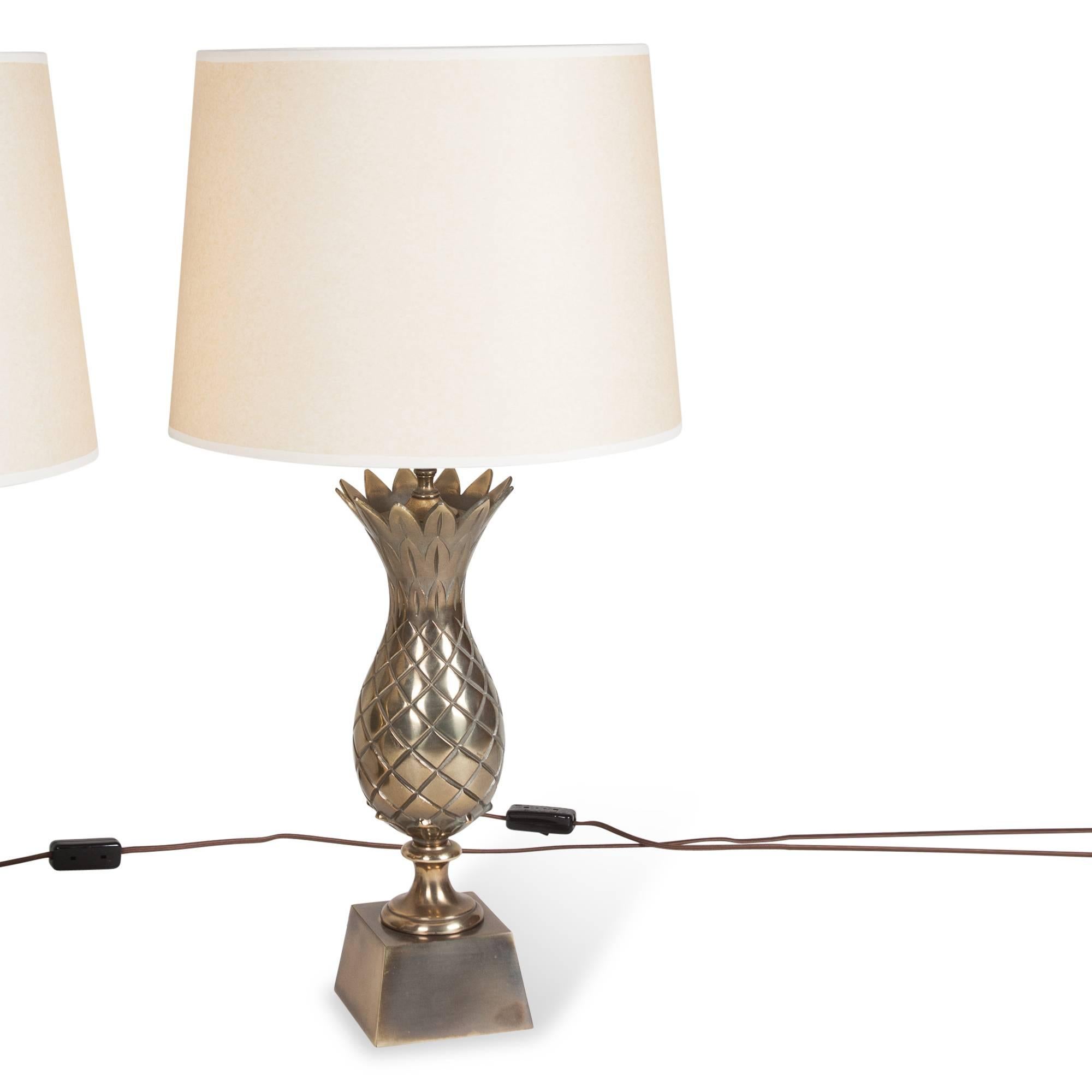 Pair of brass pineapple form lamps, the pineapple having saw tooth top border, on square tapered brass base, American 1960s. In custom linen shades. Overall height 29 1/2 in, base measures 5 in square. Shade measures top diameter 13 in, bottom