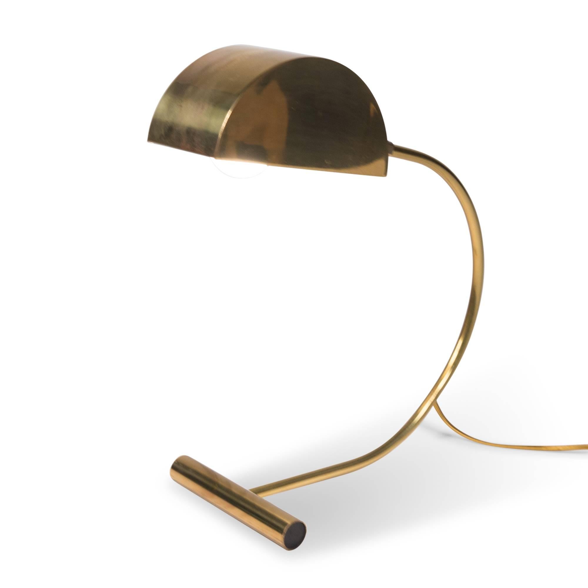 Polished brass desk lamp, the adjustable semi-circular shade mounted on a arced base terminating in a cross support, United States, 1960s. Measure: Height 14 in, depth 14 in, width 5 in.