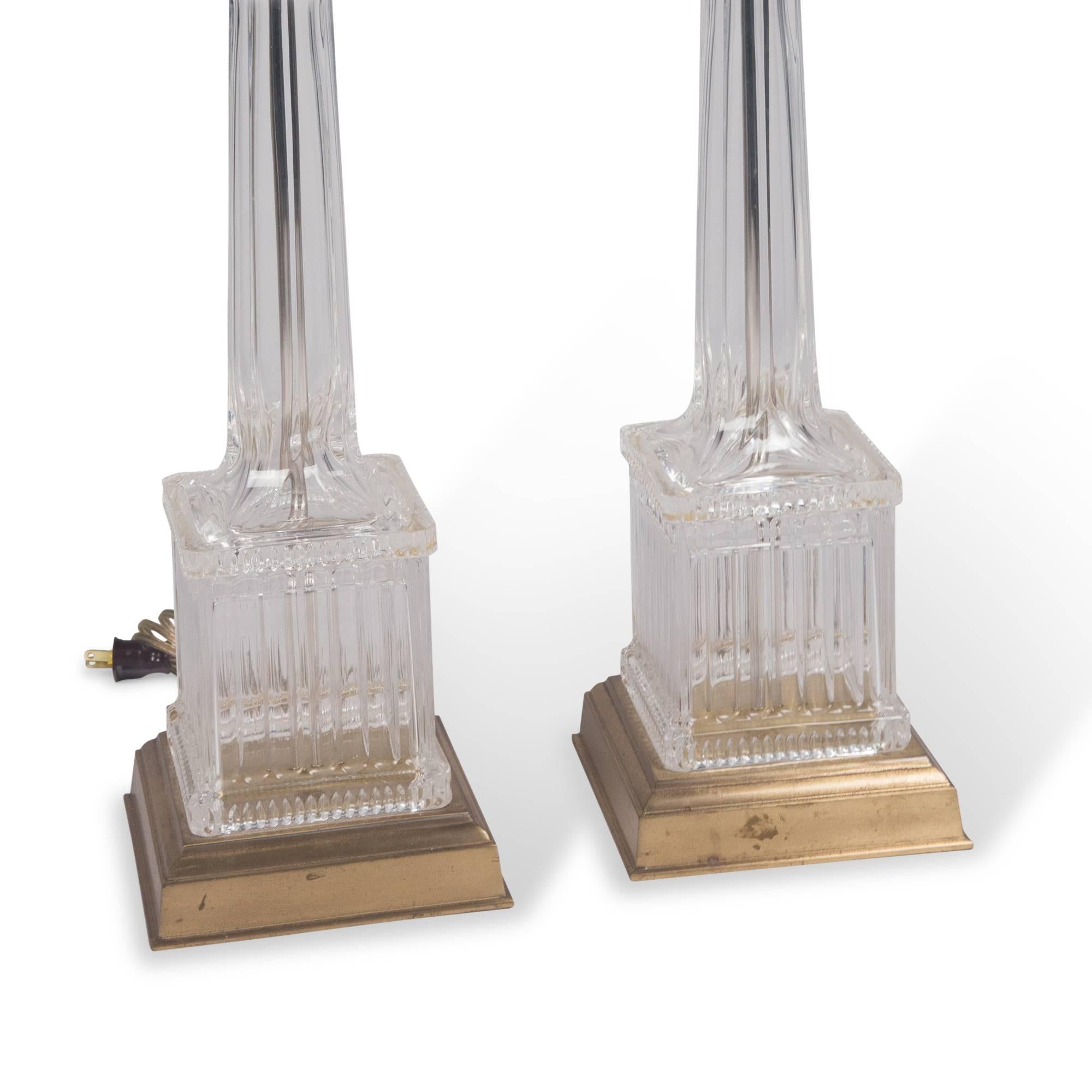 Fluted clear cast glass table lamps, rounded column-form on square base, the glass portion mounted on square brass base, with square panel finial, by Chapman, United States, 1960s. Measures: Height to top of finial 33 in, height to top of socket 23