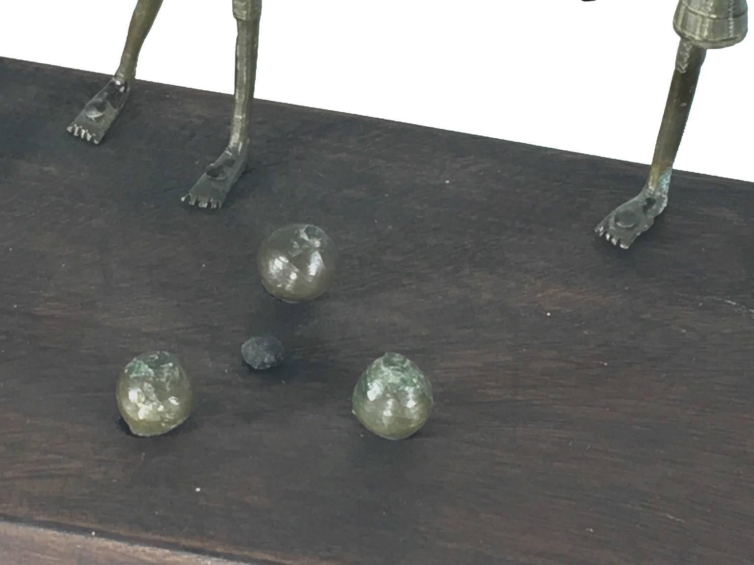 Scultura africana in bronzo e legno, con personaggi che giocano.