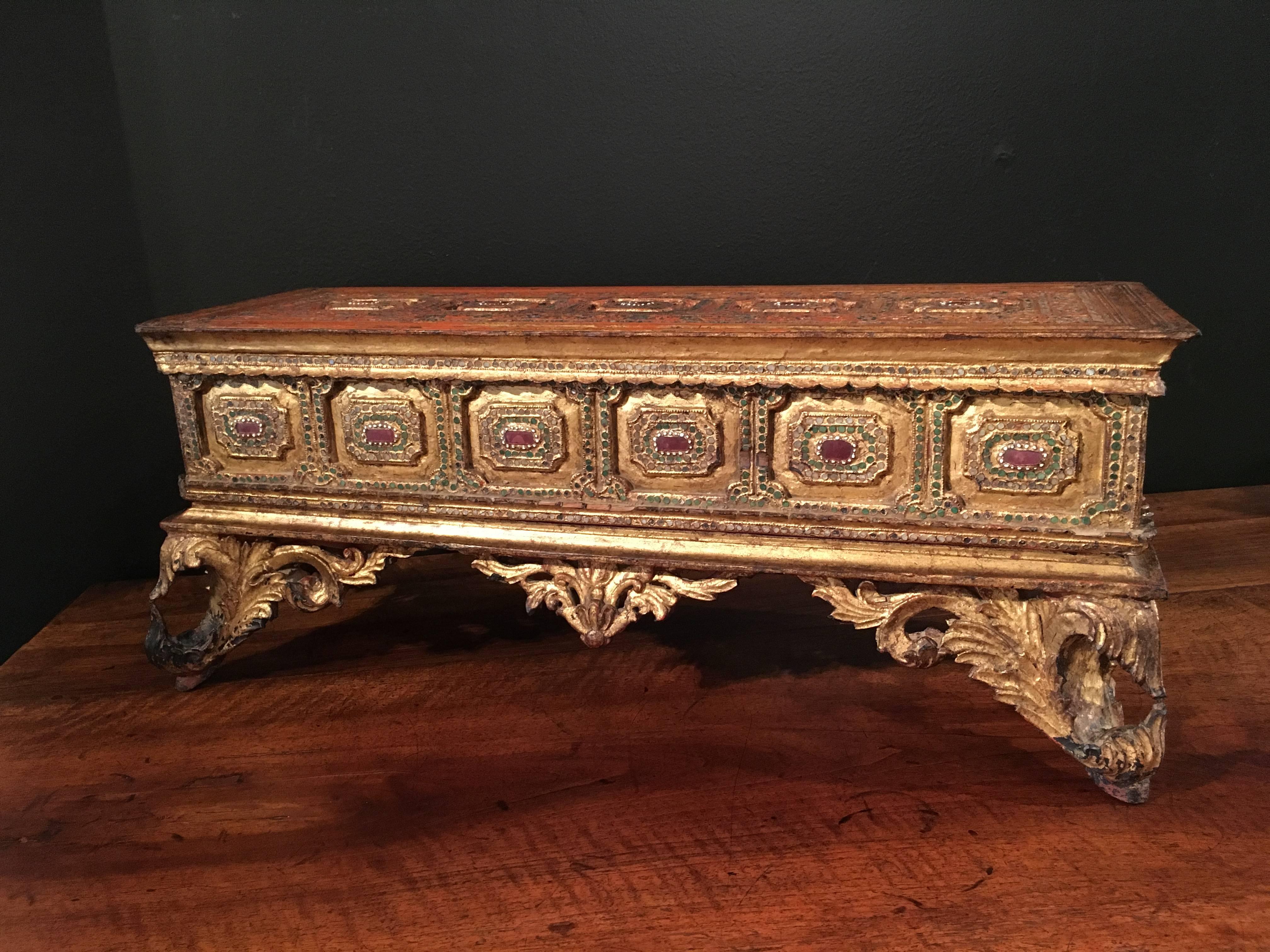 A gorgeous Burmese carved and gold leafed teakwood stand and cover for a kammavaca manuscript, late 18th or early 19th century, Burma.

The manuscript chest is heavily rococo influenced, speaking to the French presence in the region at the time. The