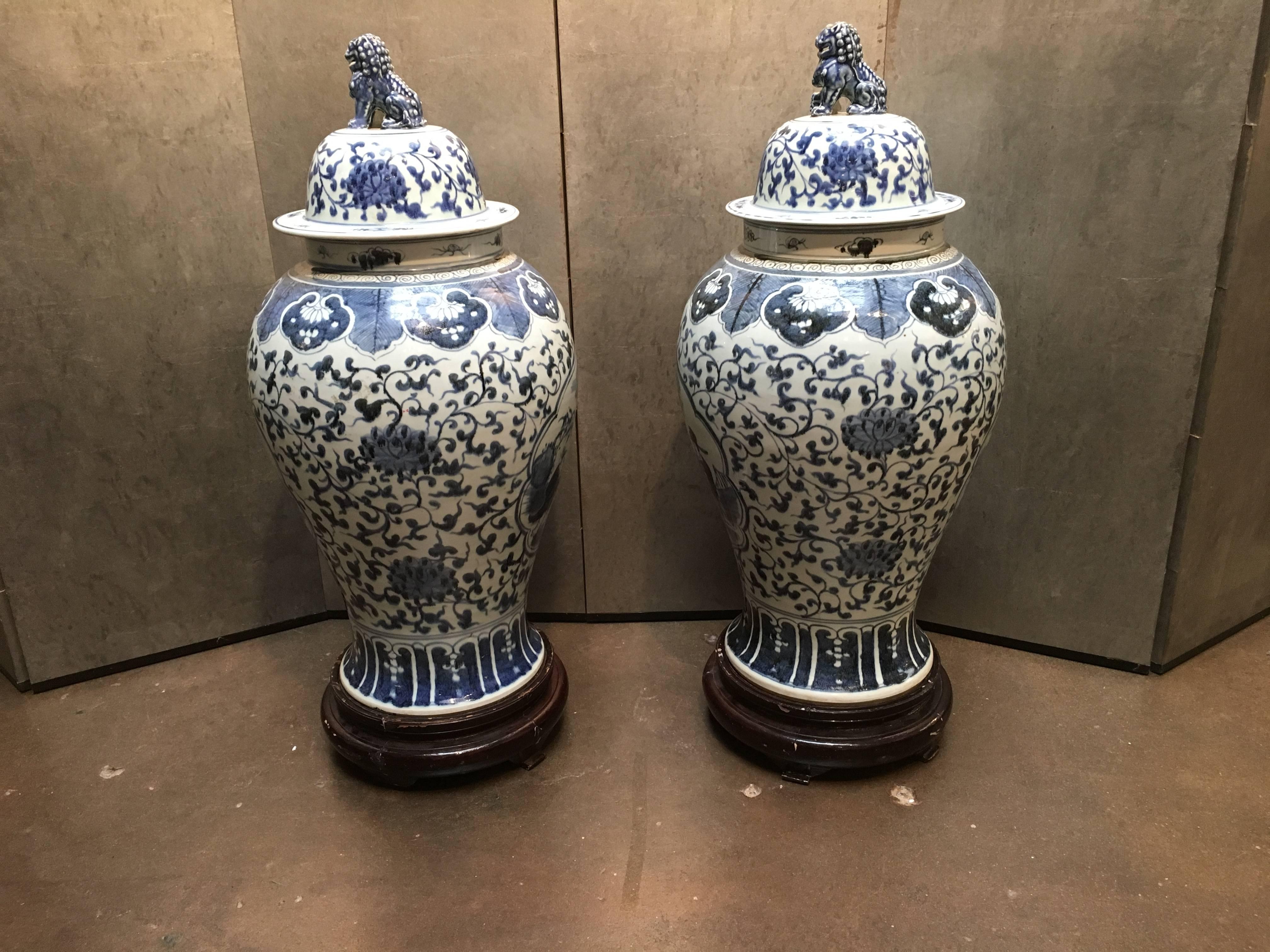 A pair of Chinese blue and white elegant, well proportioned, large scale covered baluster jars. Each with a splayed foot and low, slender waist rising up to a full body, along with broad shoulders which give way to a short, wide neck supporting the