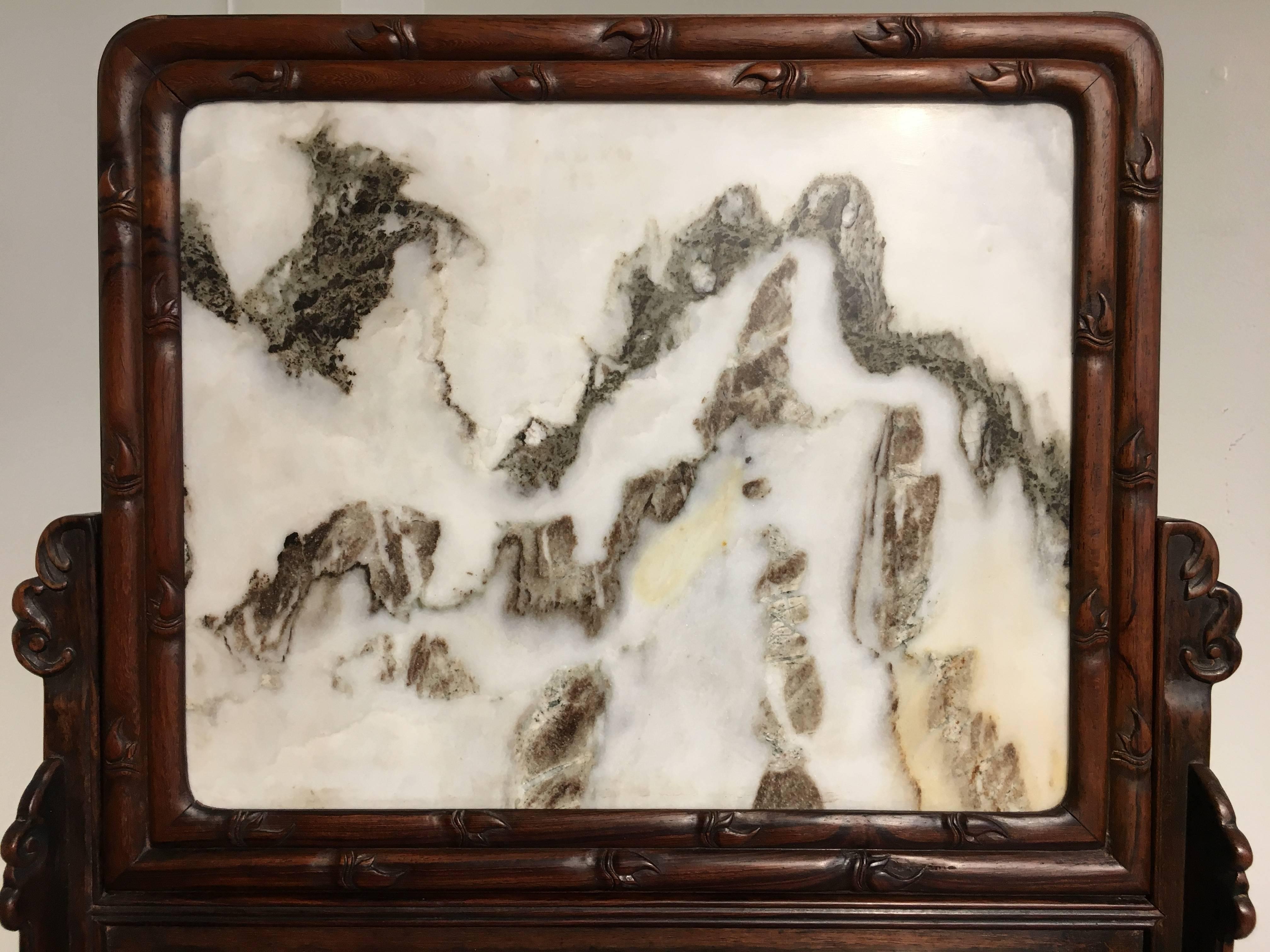 An attractive Chinese Republic period carved hardwood and Dali marble table screen. The well patterned Dali marble dream stone evocative of a misty mountain landscape and set in a hardwood frame carved to imitate bamboo.
The screen set in a