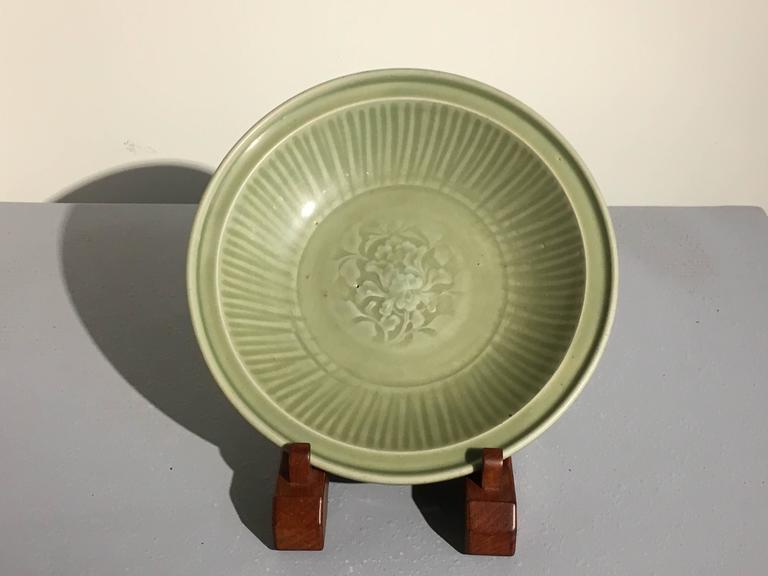 A beautiful Chinese celadon glazed deep dish with an impressed peony design to the center, Ming Dynasty, circa 1400, Longquan kilns, China. 

The lovey dish covered in an attractive deep celadon green, bordering on olive, and featuring a central