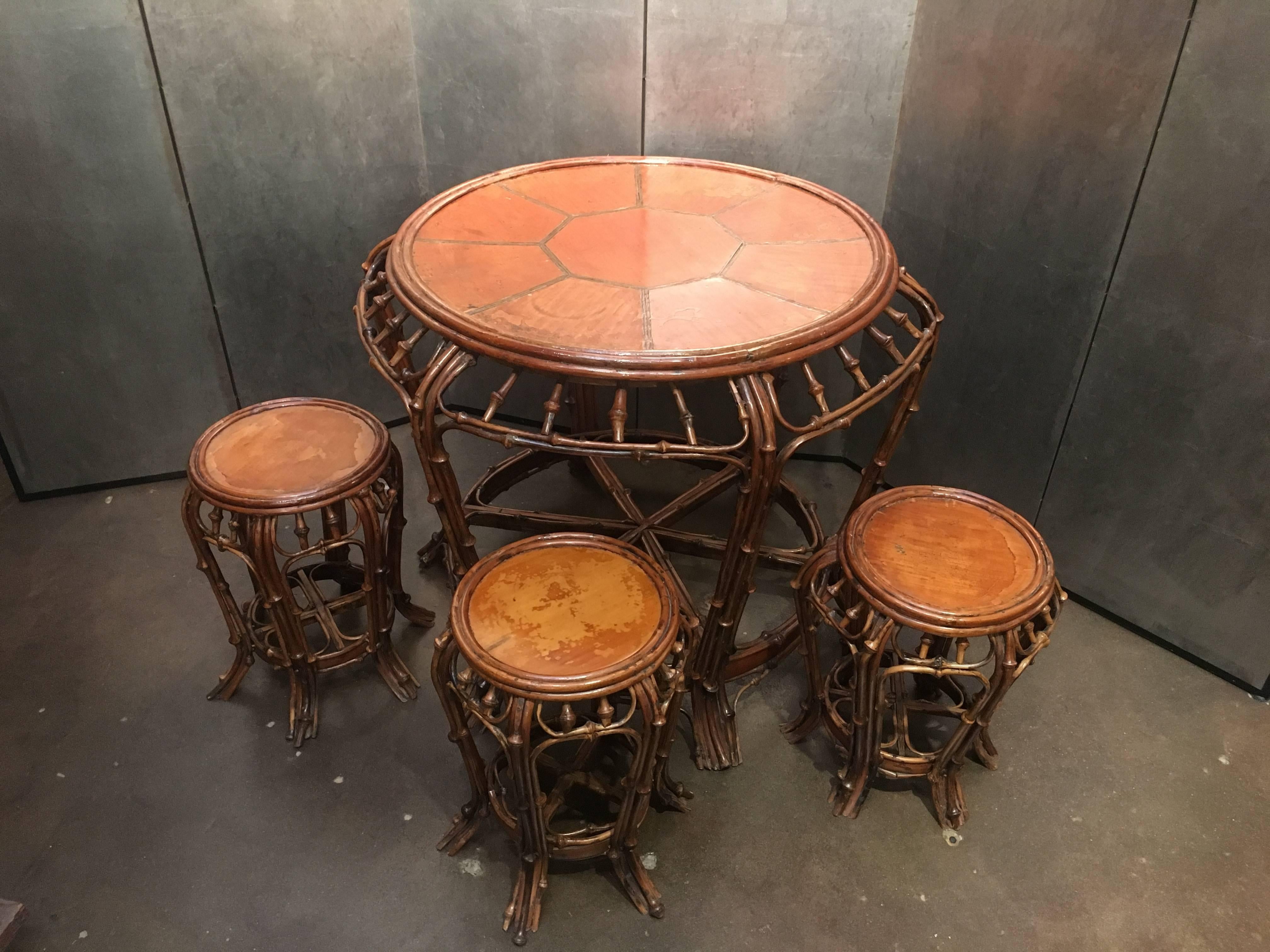 A stunningly elegant 19th century Chinese bent bamboo table with three stools. The body and legs of the table comprised of bent stalks of knobby bamboo. The circular top crafted from large sections of flattened bamboo. The stools fashioned in the