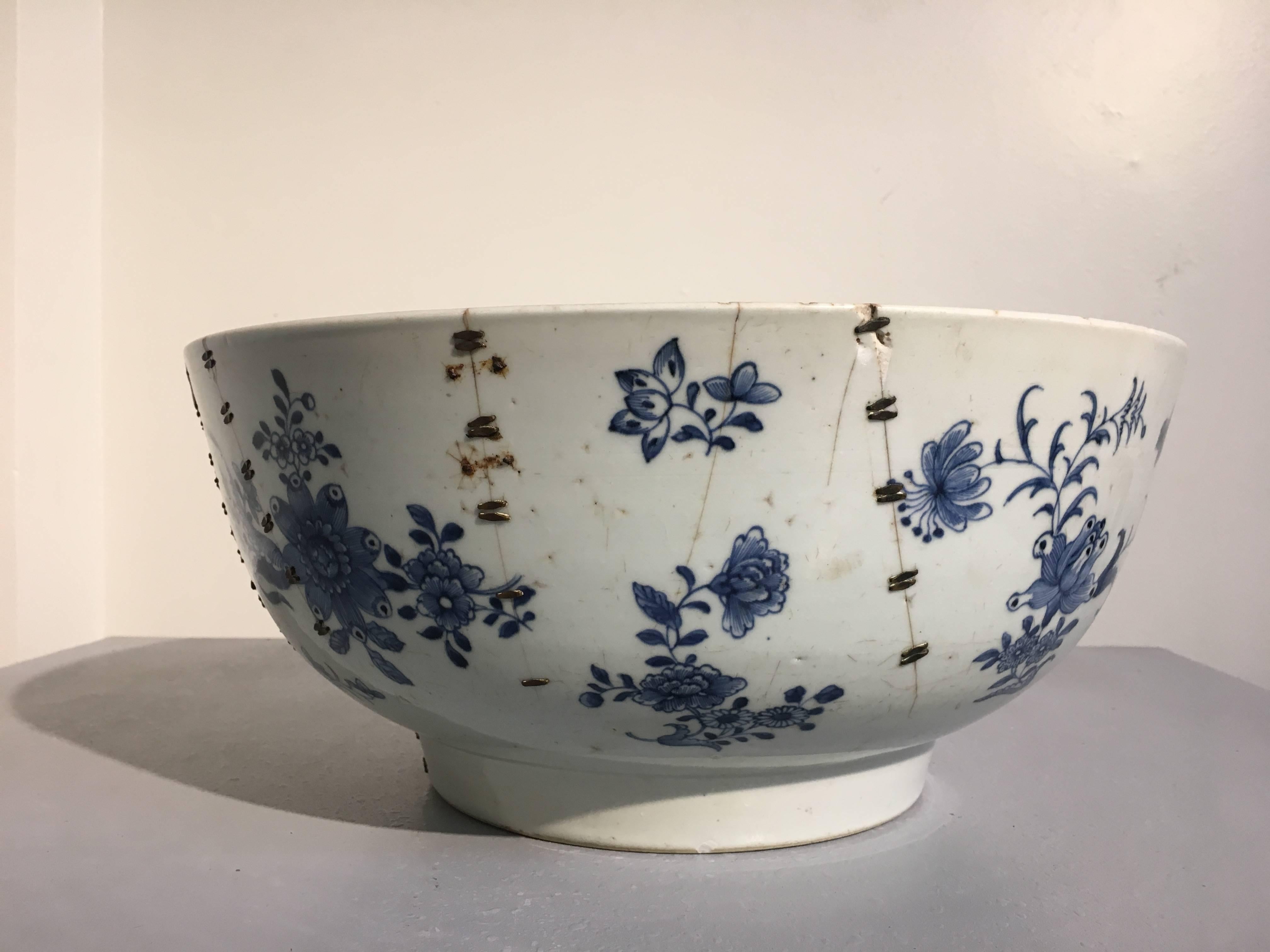 A remarkable large Chinese export blue and white punchbowl painted with a floral and brocade design, and featuring a stunning staple repair, 18th century, China. 

While of large size and beautifully painted, what makes this piece exceptional is the