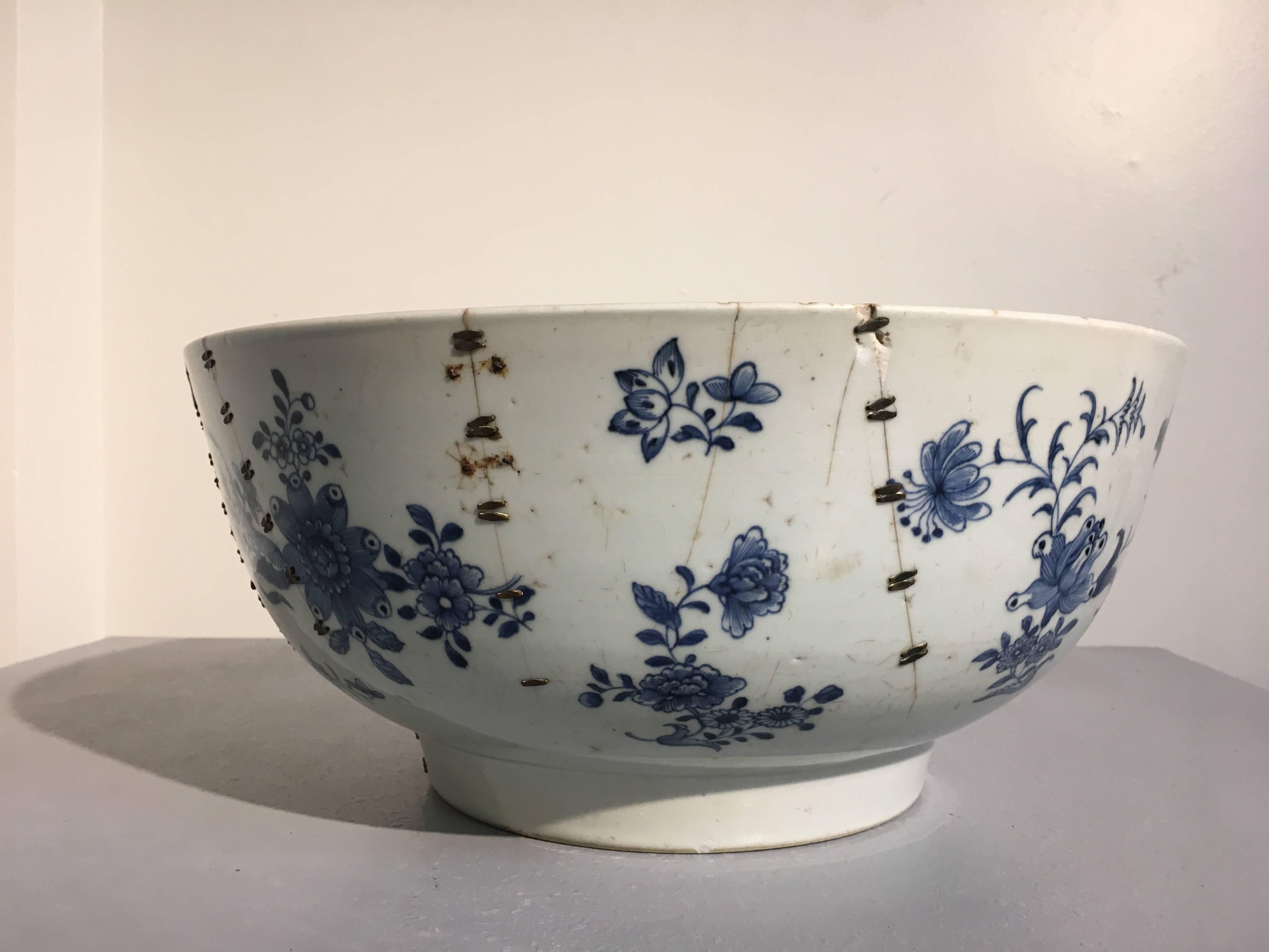 Una notevole grande punchbowl cinese da esportazione in bianco e blu dipinta con un disegno floreale e di broccato e con una straordinaria riparazione della graffa, XVIII secolo, Cina. 

Sebbene sia di grandi dimensioni e ben dipinto, ciò che rende