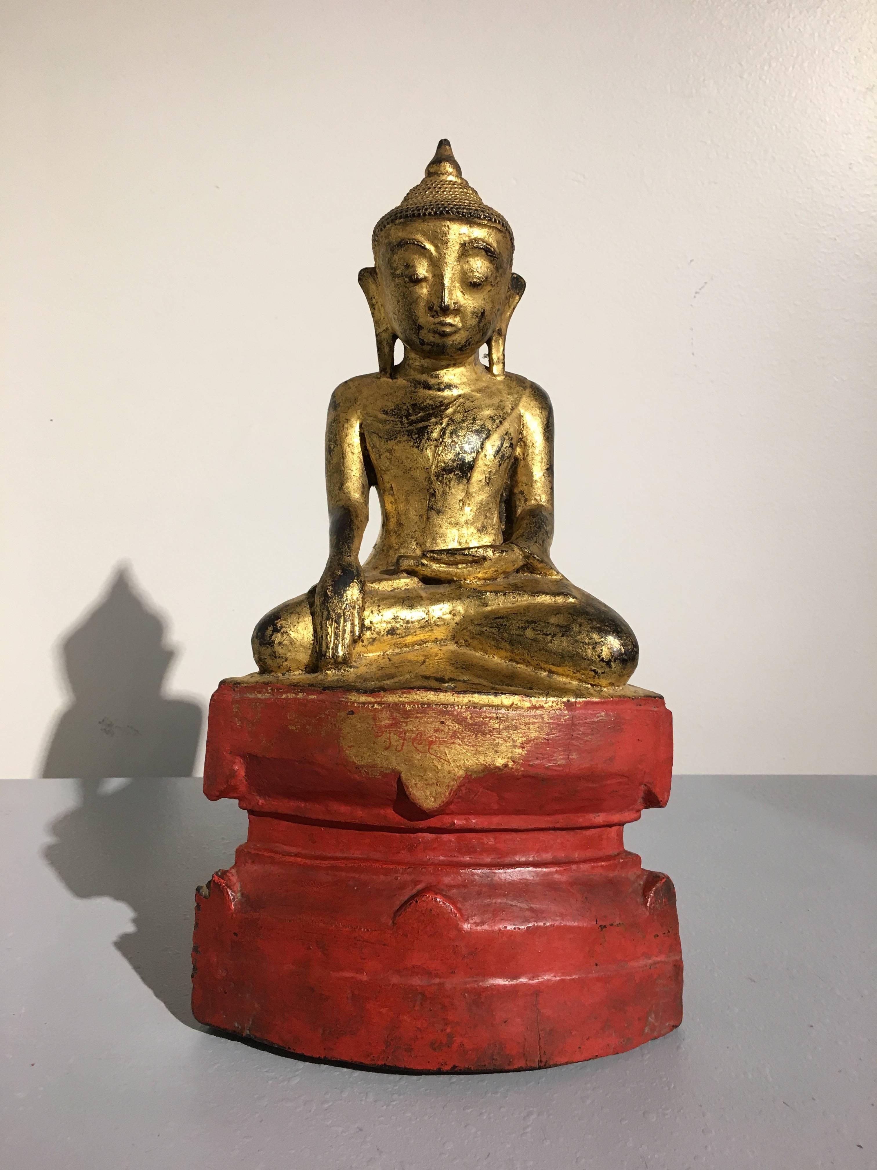 A rare and exquisite 18th century Ava period Shan Burmese figure of the Buddha.
Carved from a single block of wood, lacquered and gilt, the immensely serene figure is portrayed seated upon a raised throne, hands in bhumisparsha mudra, the gesture