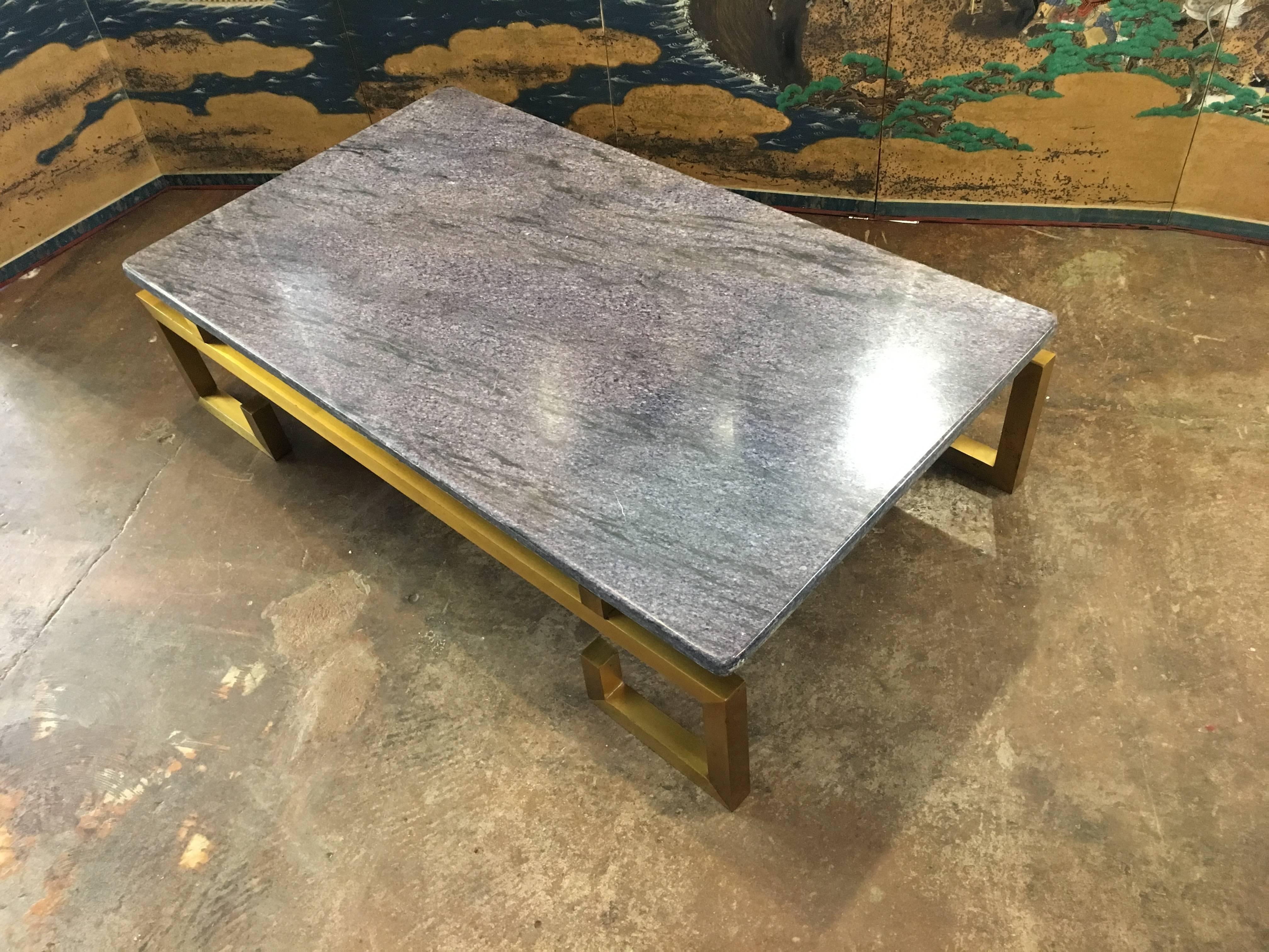 A stunning and chic French Modern coffee table in the style of Guy Lefevre and Maison Jansen, circa 1970s. 
The low coffee table of elegant proportions, comprised of a brass base with Greek key fret feet and a massive single slab blue hued marble