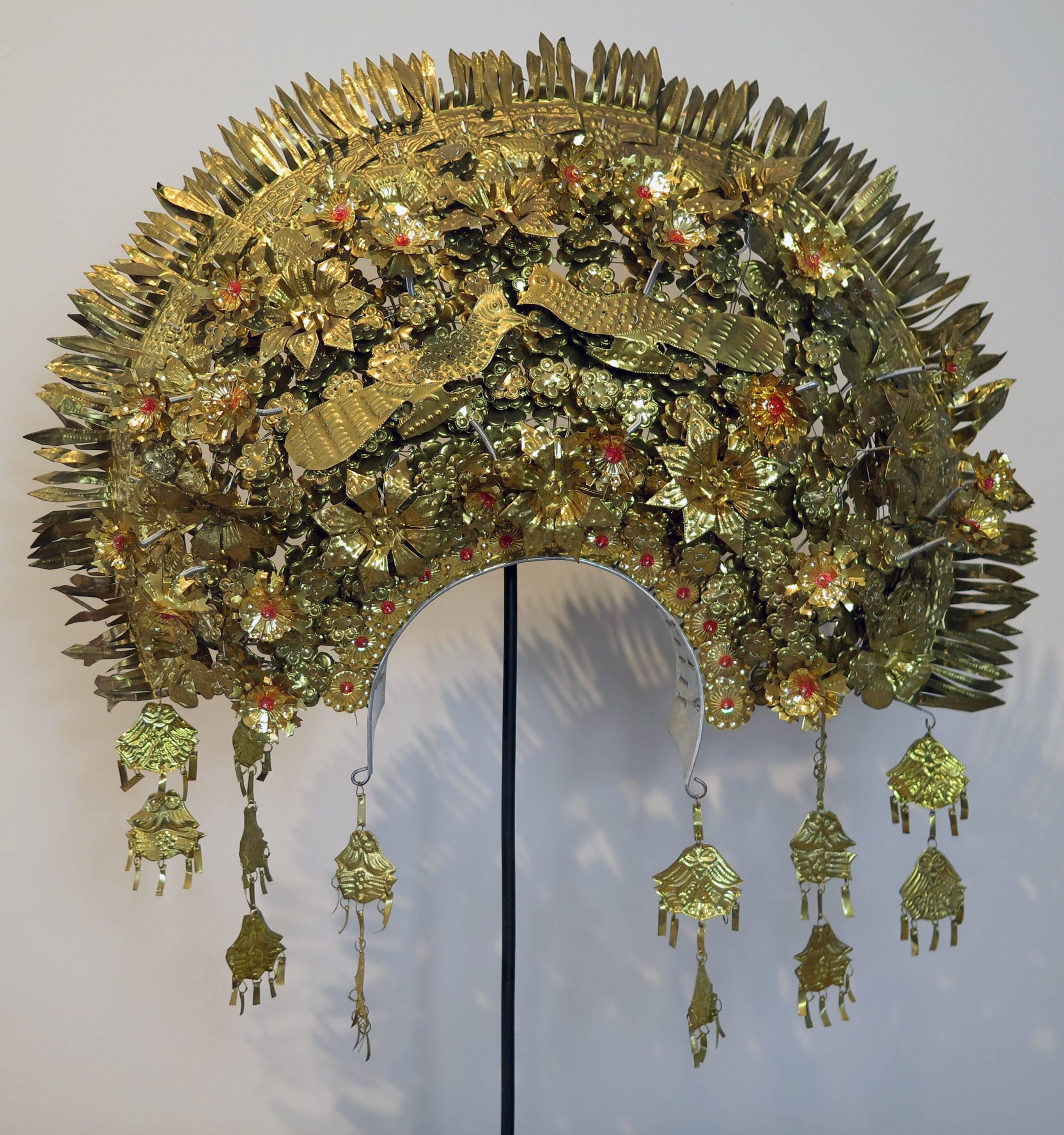 A stunning and elaborate bridal headdress from he Minangkabau peoples of Sumatra, Indonesia, circa 1960s.
This spectacular headdress is composed of hundreds of embossed gilt metal pieces masterfully joined together. Many components on springs or