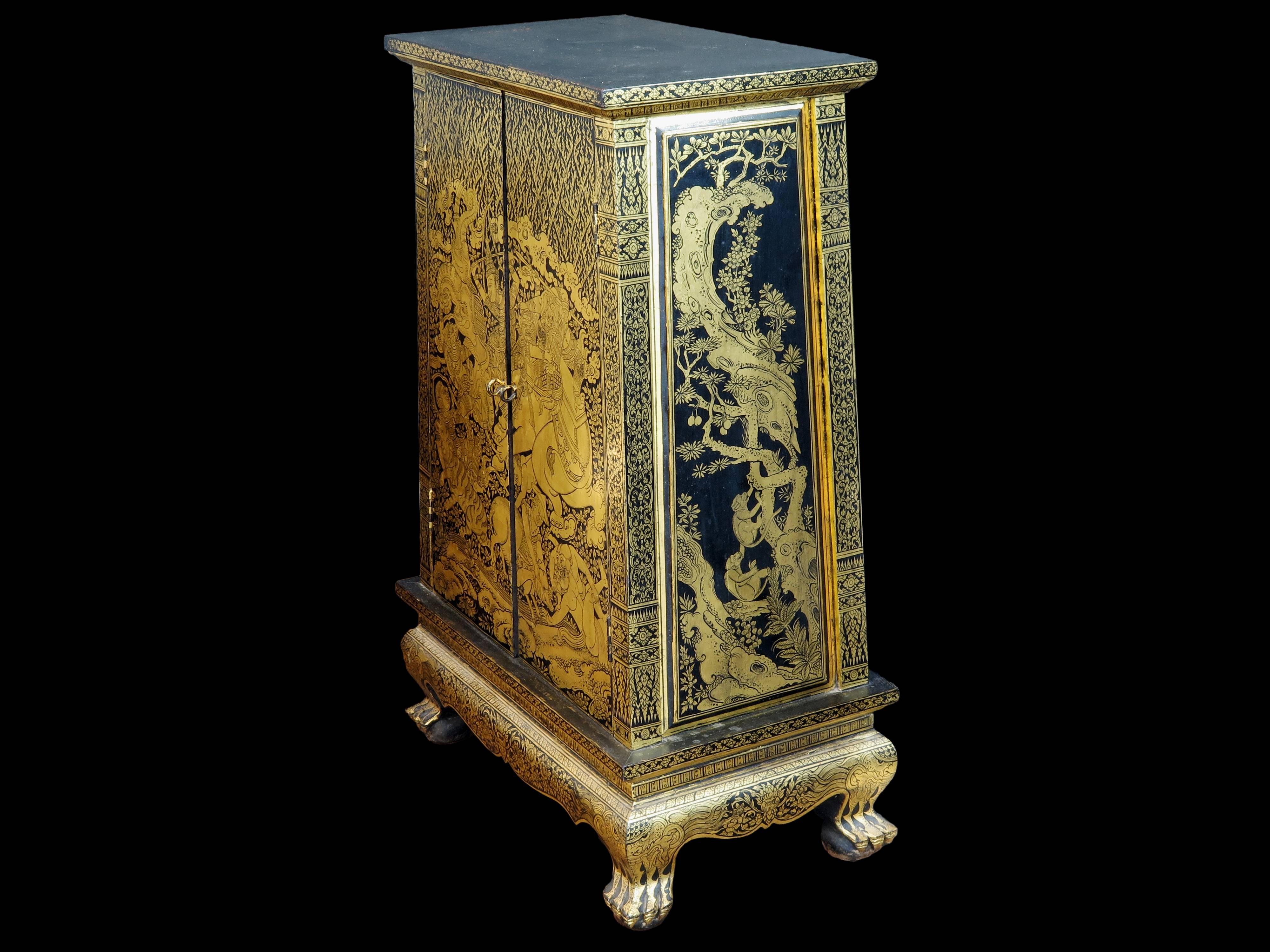 A stunning Thai black lacquer and gold leaf decorated teak wood manuscript cabinet, mid 20th century, Thailand.

Of slightly tapered form, with two doors and two interior shelves, the teak wood cabinet is supported by four clawed feet. 
Built from