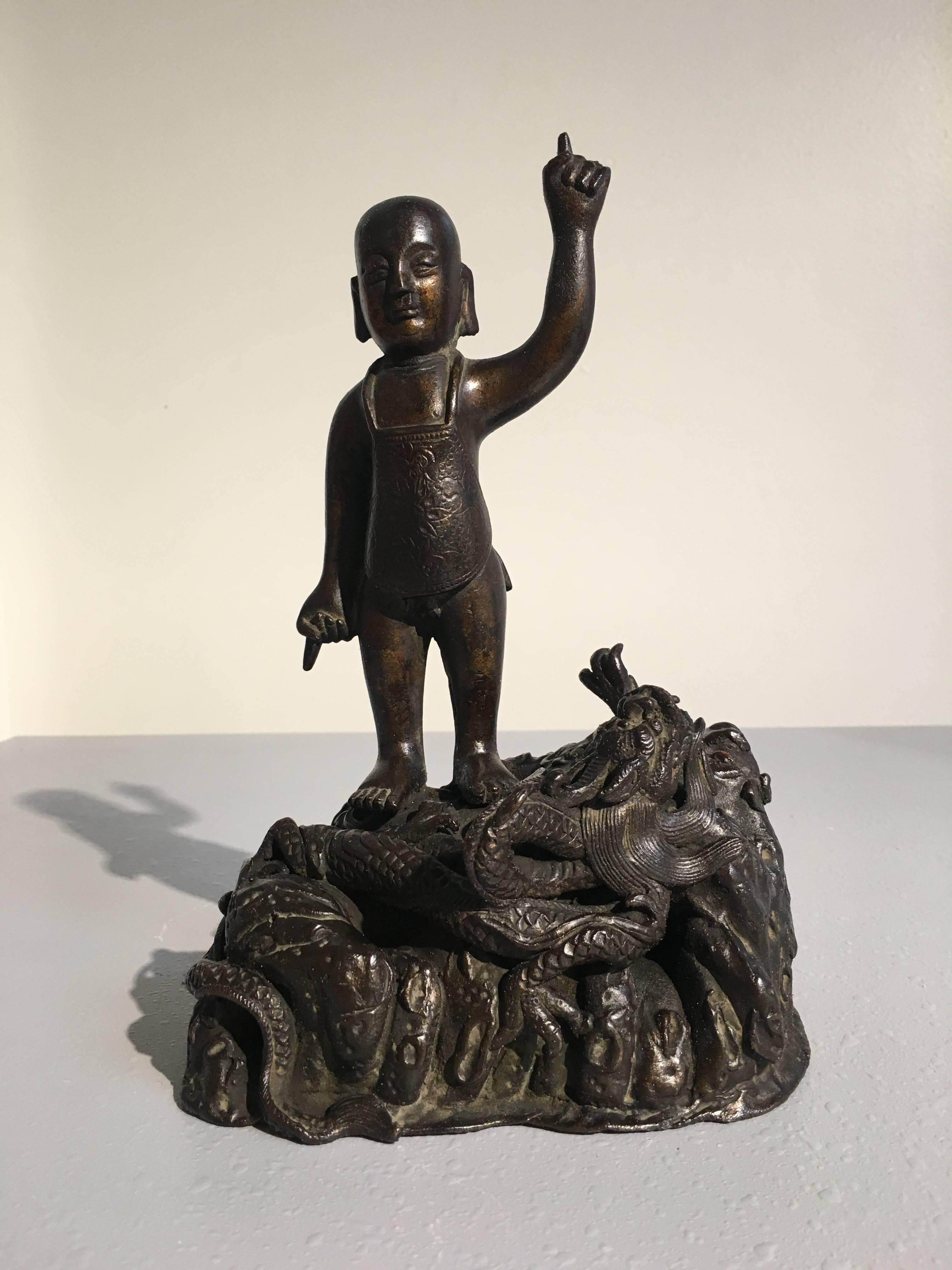 Rare et inhabituelle figurine en bronze de la dynastie chinoise Ming représentant le Bouddha enfant. Le jeune prince Siddhartha, qui deviendra le Bouddha, est représenté debout, une main dirigée vers le ciel, l'autre vers le sol. Il est nu, à