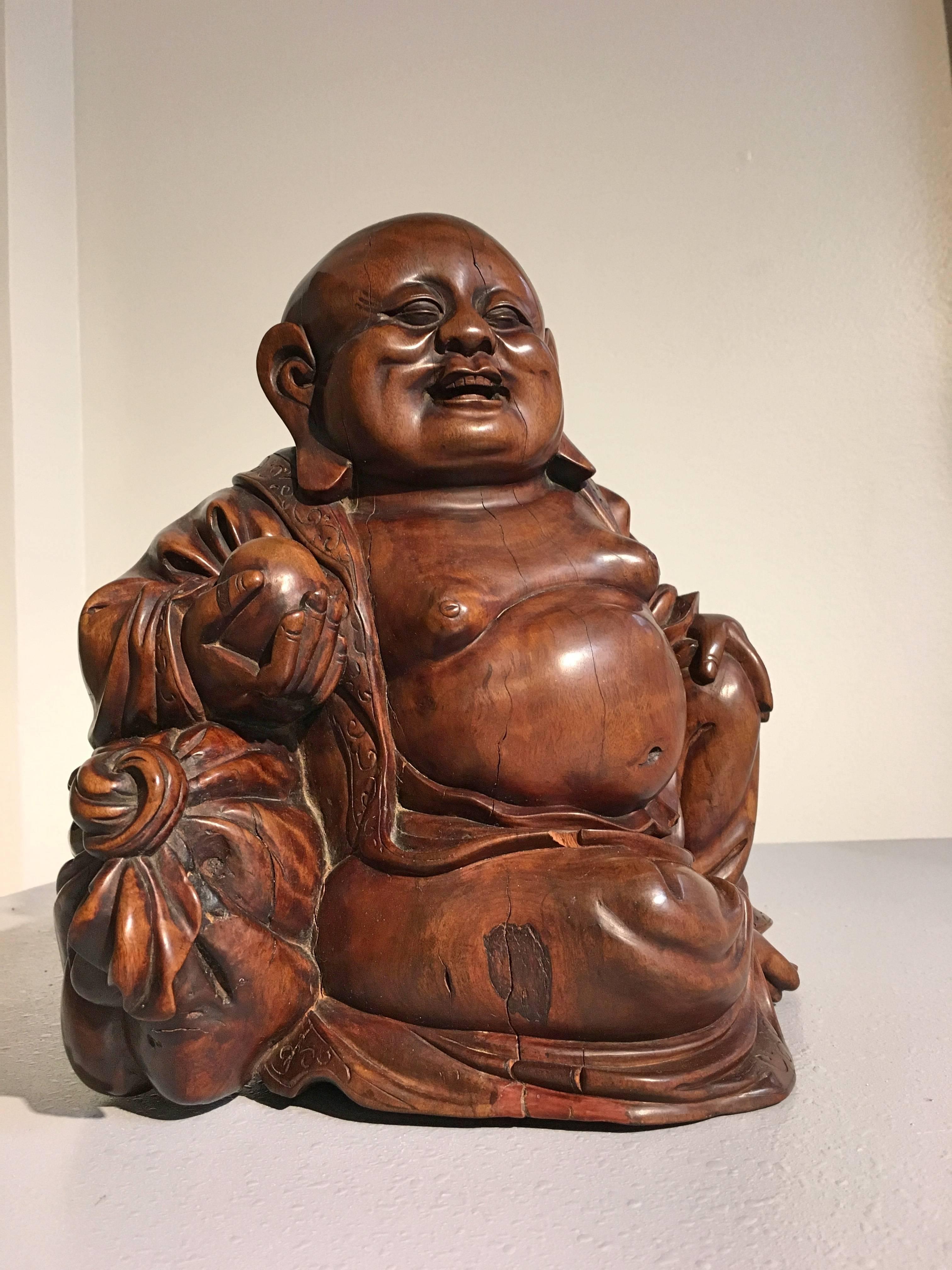 A  well carved hardwood carved figure of Budai, late Qing Dynasty, mid 19th century, China.
Carved from an extremely dense hardwood, with a rich, well figured grain that shimmers in the light. The top of his head displaying a warm and shiny patina